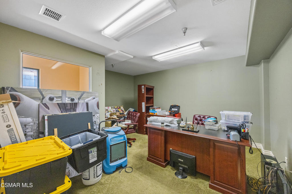 Office with a large wooden desk, burgundy chairs, and storage bins.