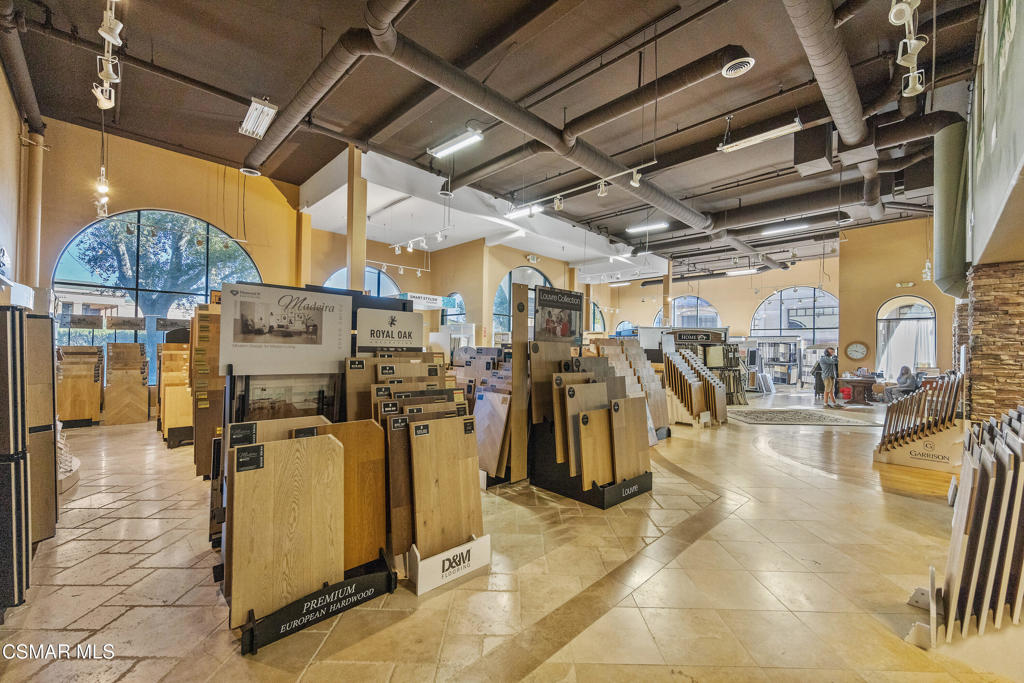 Flooring showroom with wood sample displays, arched windows, and an exposed industrial ceiling.