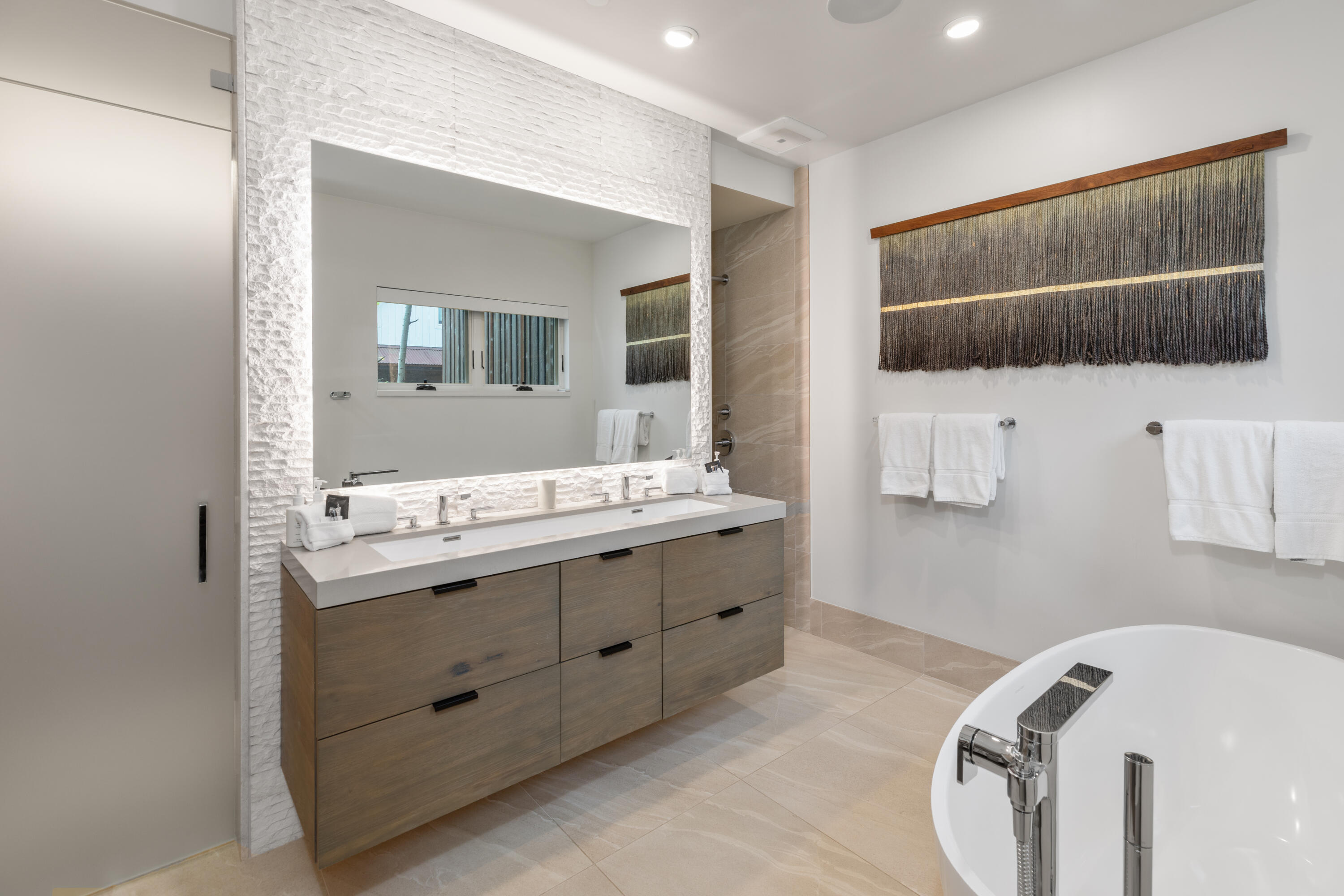 Modern bathroom with a wood double vanity and freestanding soaking tub.