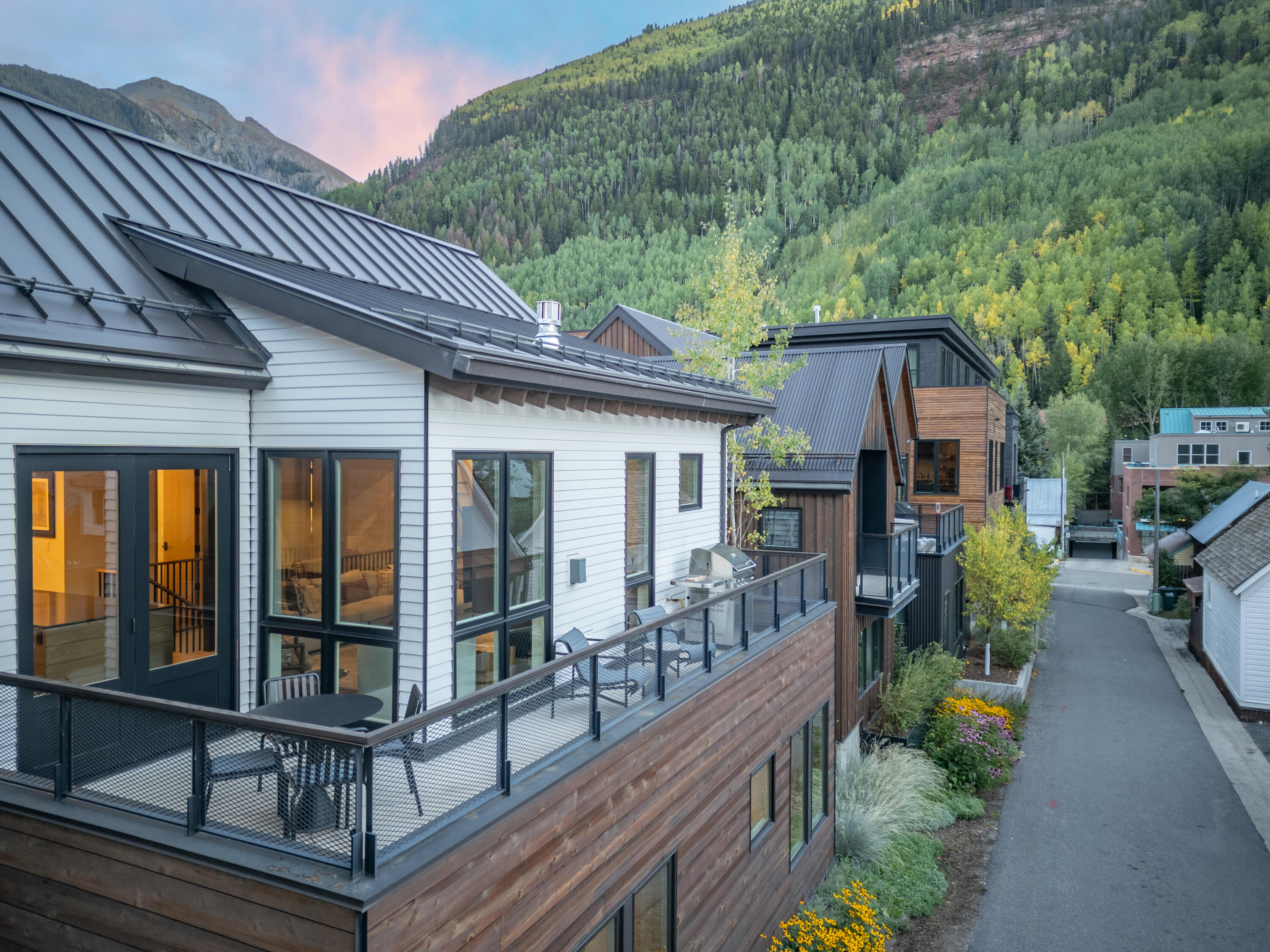 Mountain residence with a spacious terrace and wood siding beneath forested slopes.