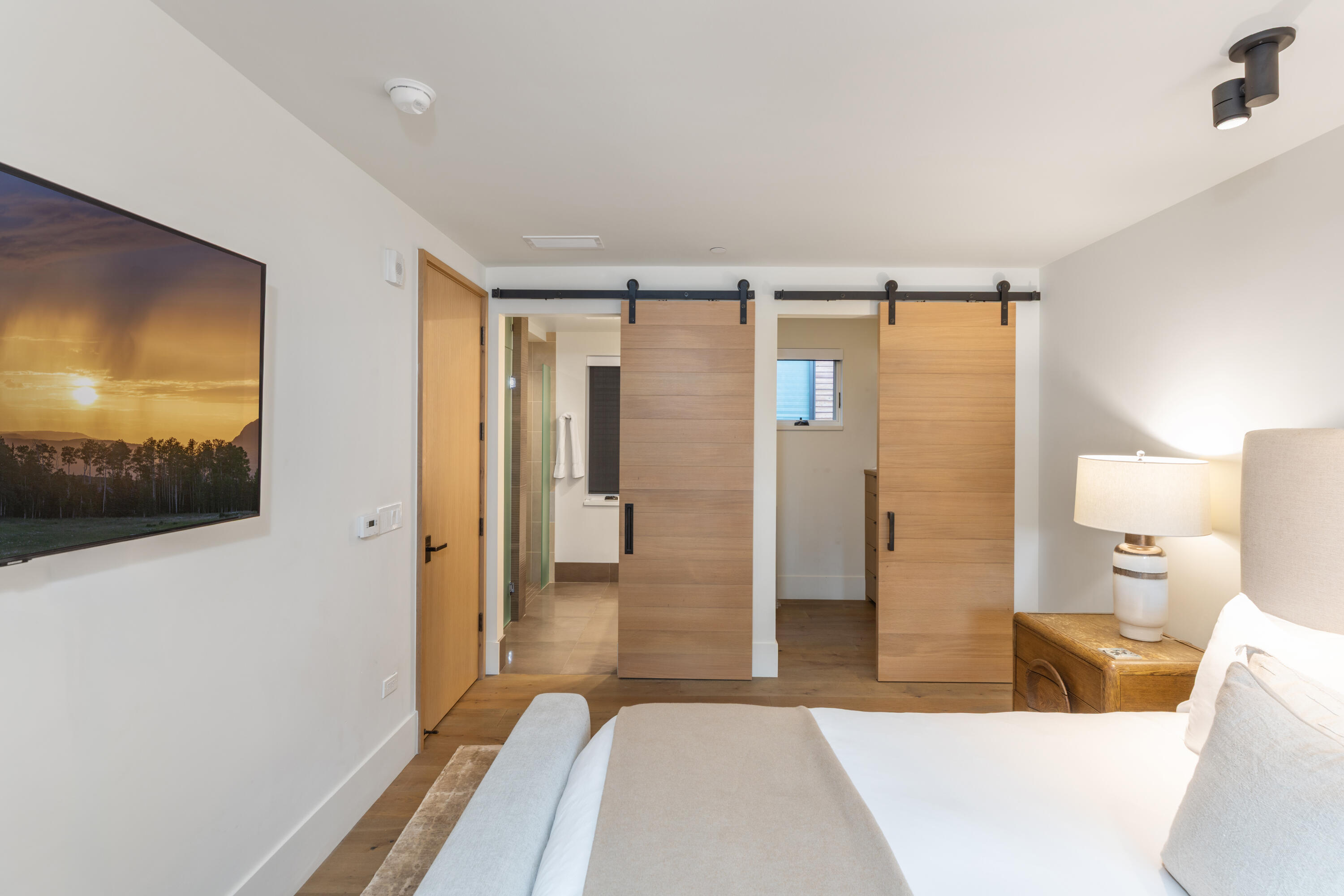 Furnished bedroom with sliding wooden barn doors and a view into the bathroom.