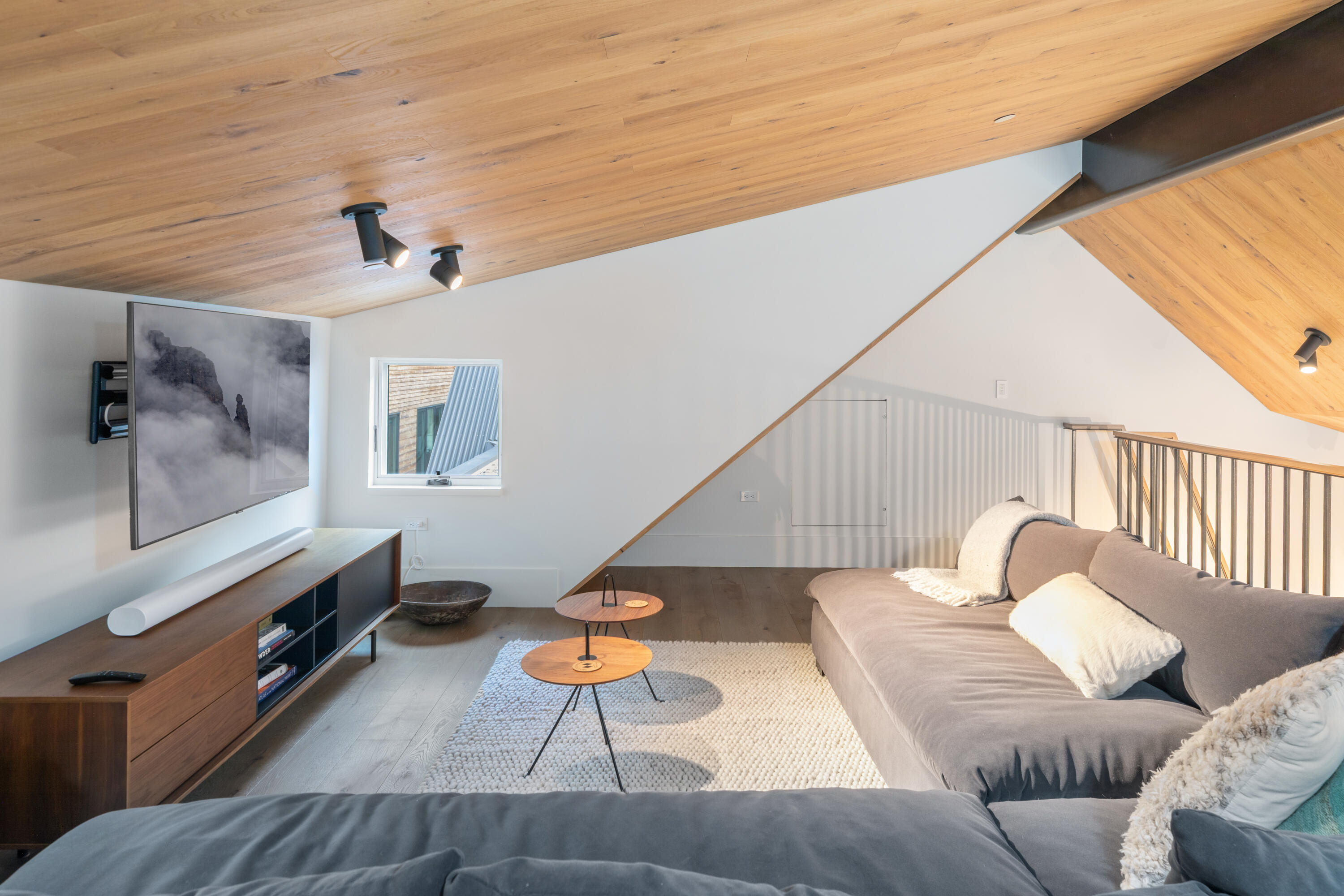 Living room with a vaulted wood ceiling, gray sectional, and loft railing.