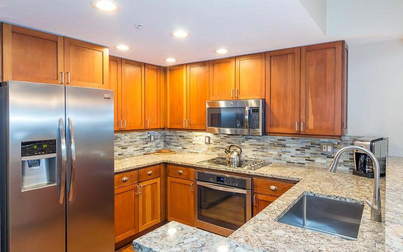 Kitchen with warm wood cabinets, granite counters, stainless steel appliances, and a large sink.
