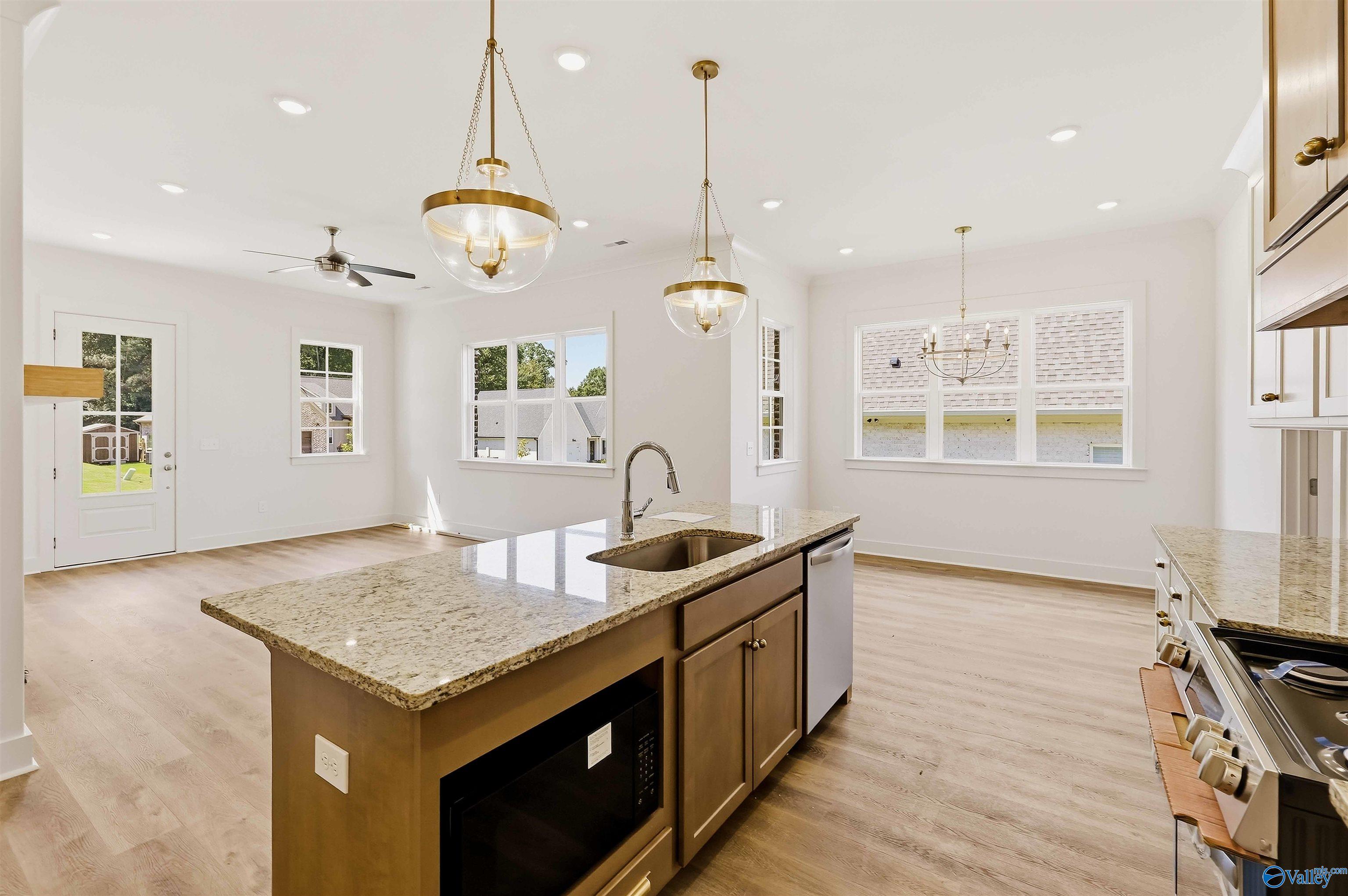 Open kitchen with granite island, pendant lights, and adjoining dining area.