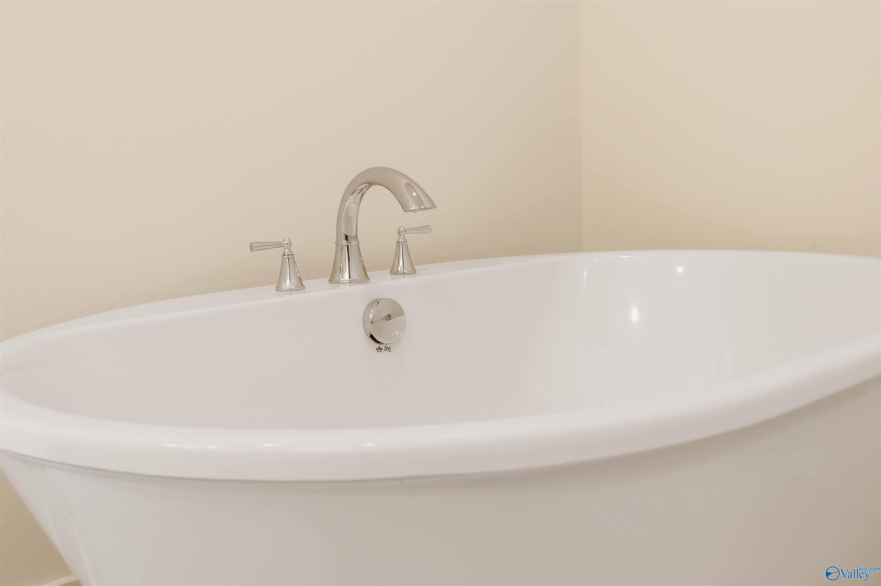White freestanding bathtub with polished metal faucet and handles.