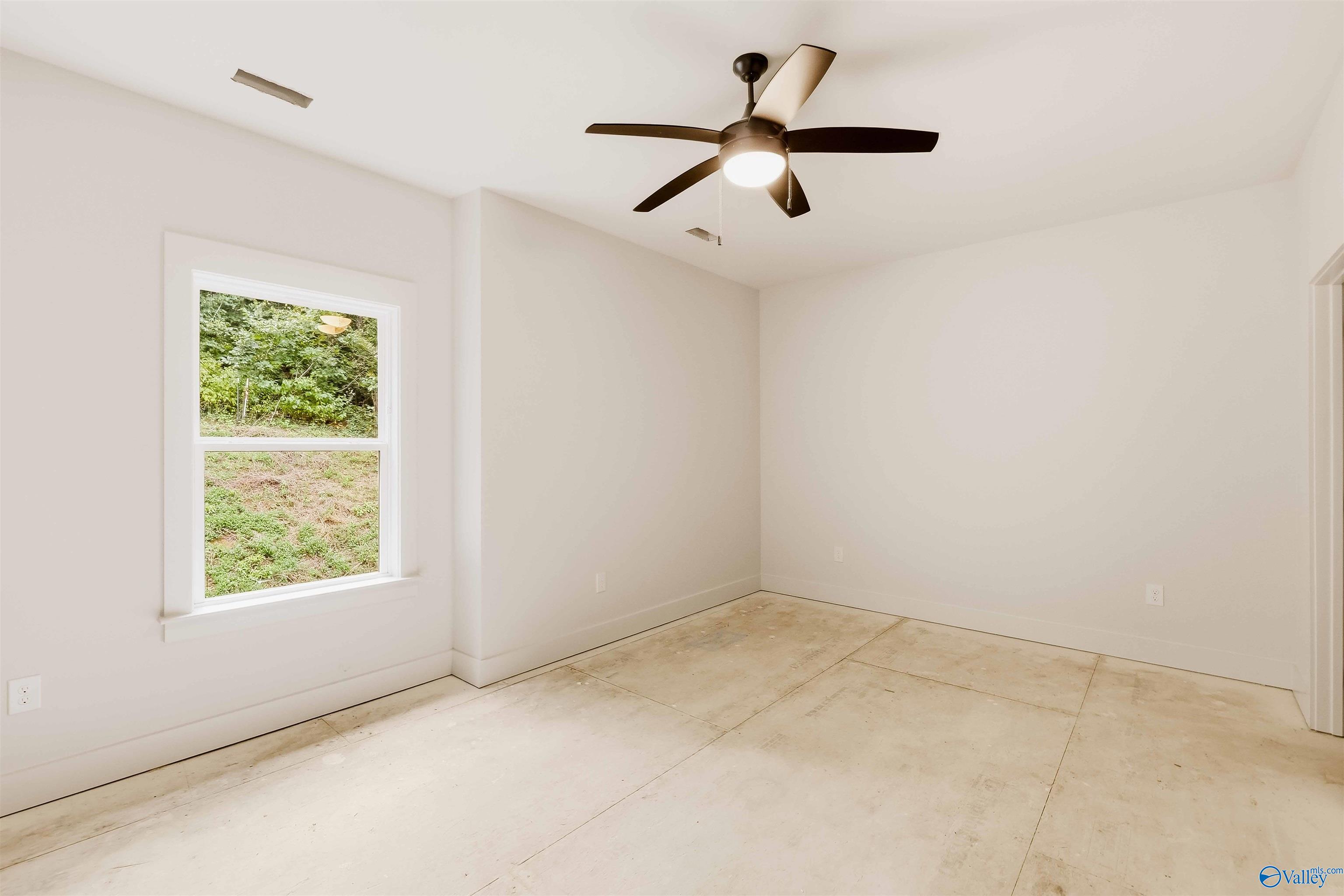 Empty room with a ceiling fan, large window, and light-colored floor.