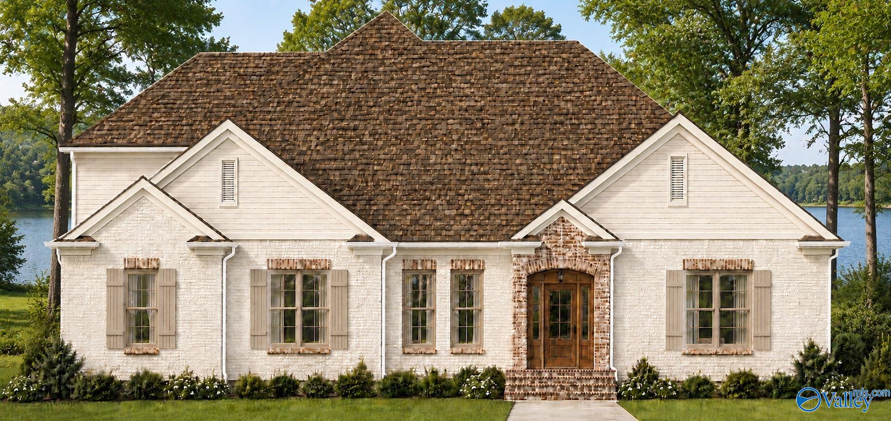 White brick home with a broad shingle roof and central wooden entry beside the water.