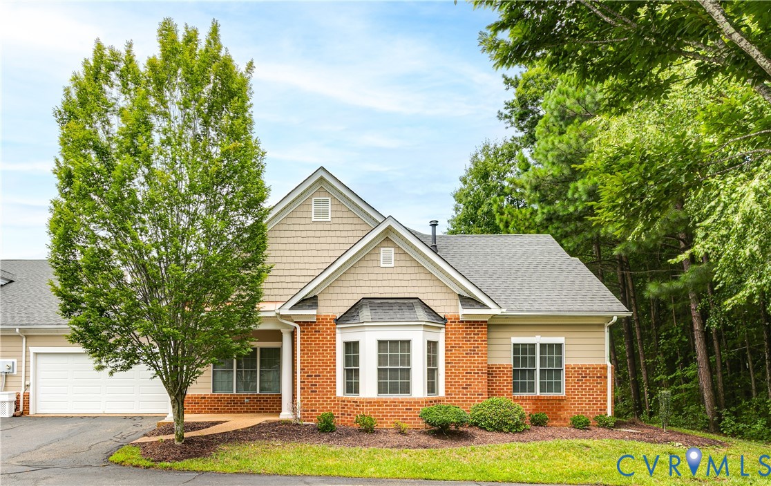 Home with red brick and beige siding, a white garage, and a front bay window.