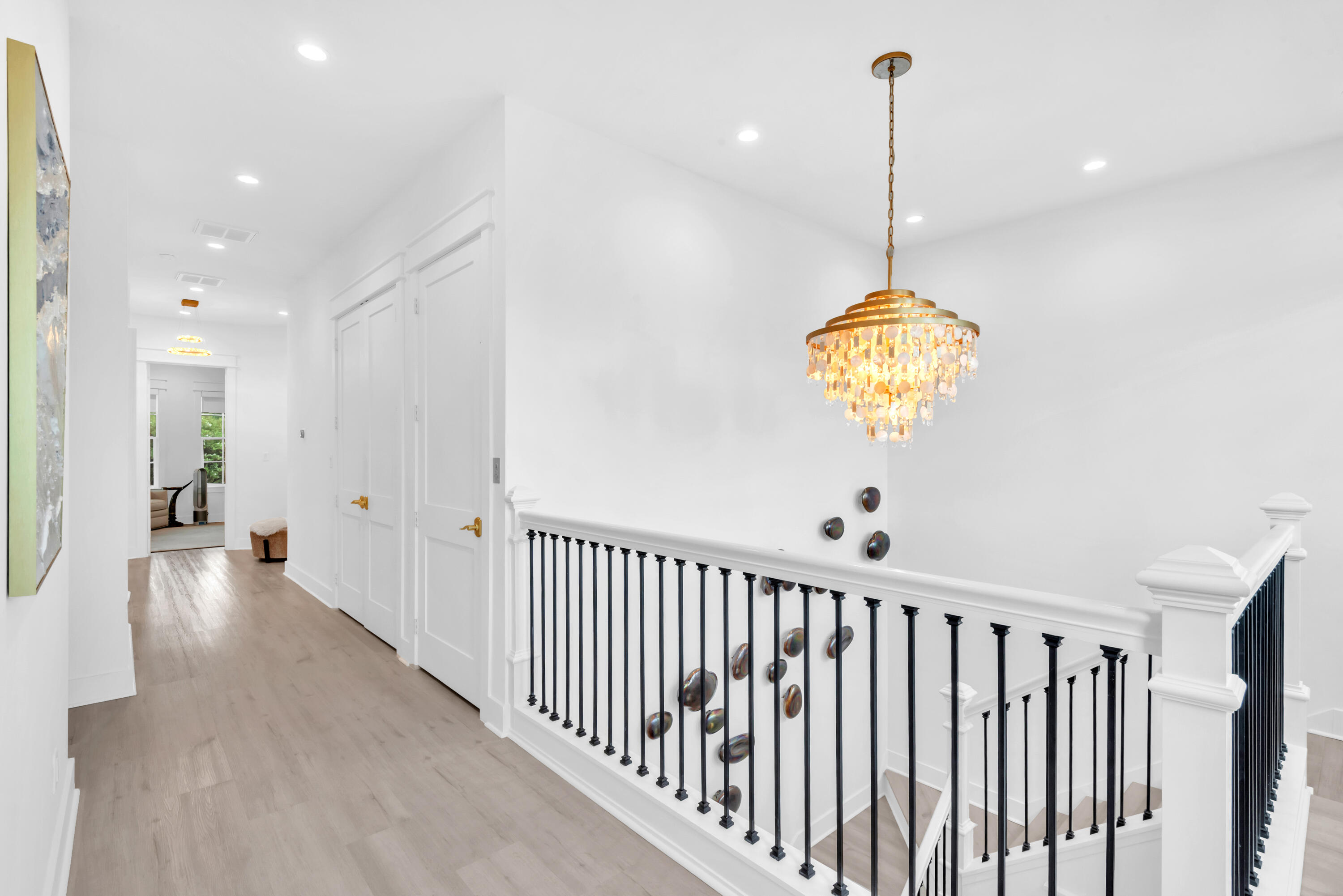 Upstairs landing with black stair railings and a gold crystal chandelier over the stairwell.