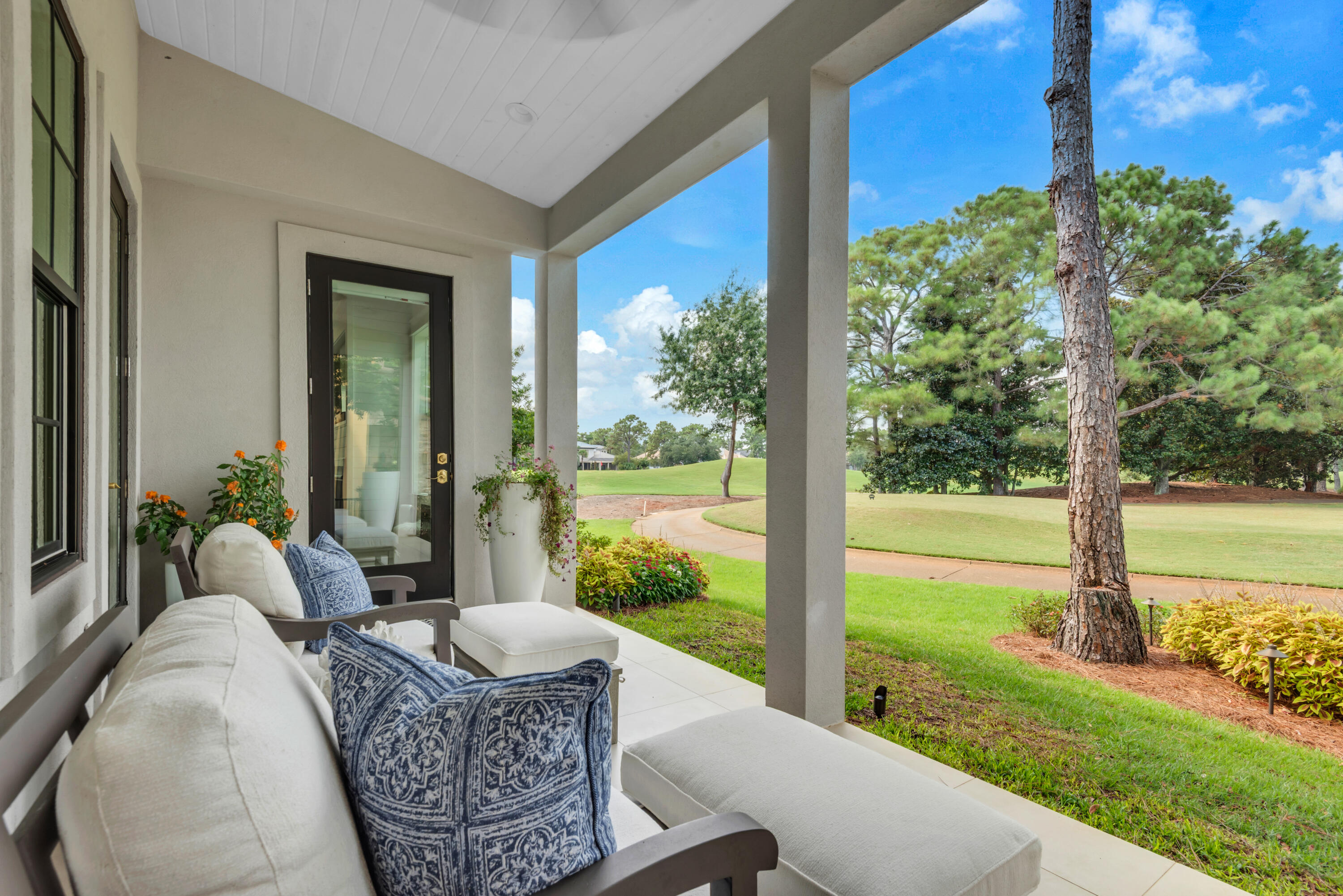 Covered patio with cushioned seating overlooking a manicured golf course.