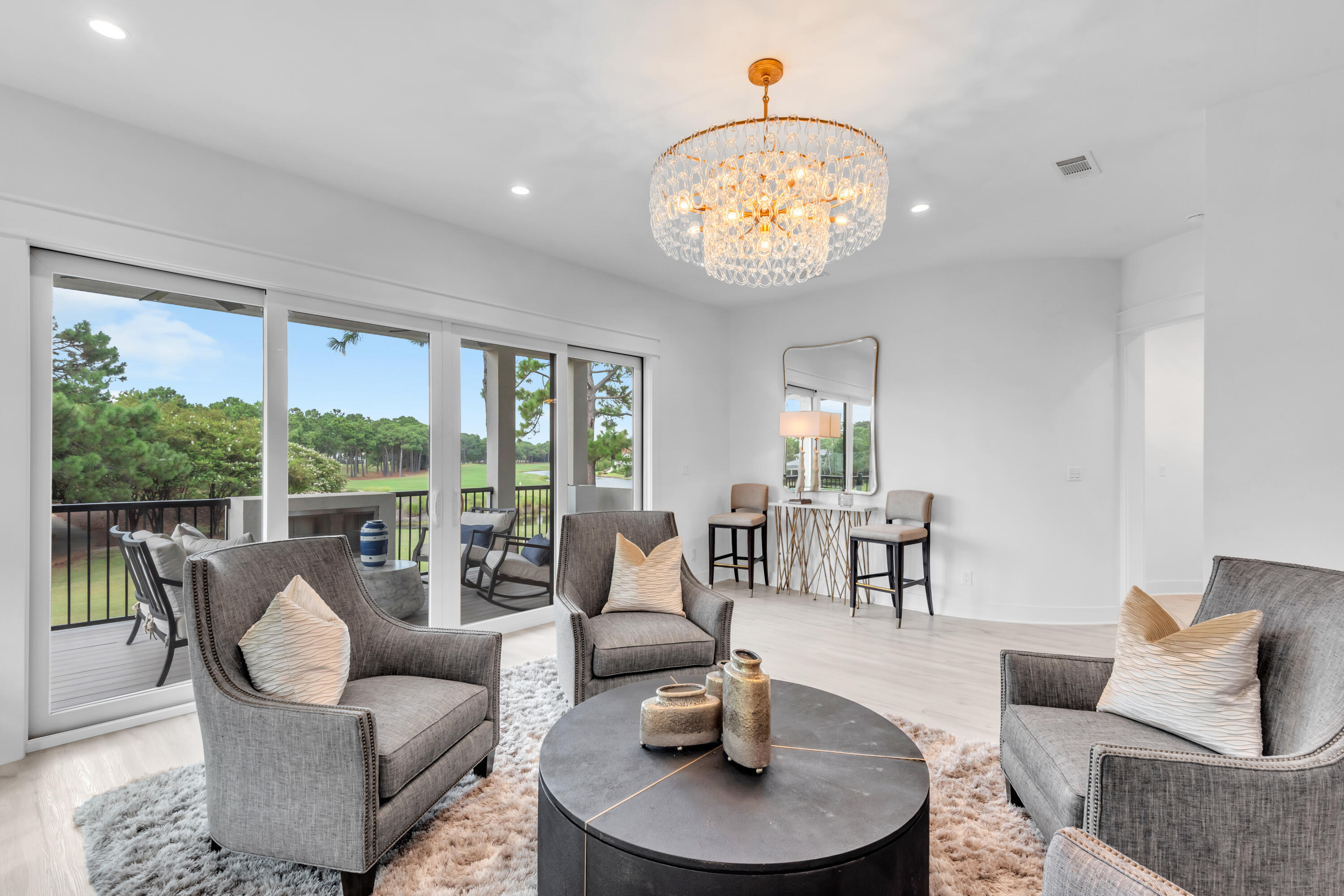 Furnished living room with a crystal chandelier and sliding doors overlooking a golf course.