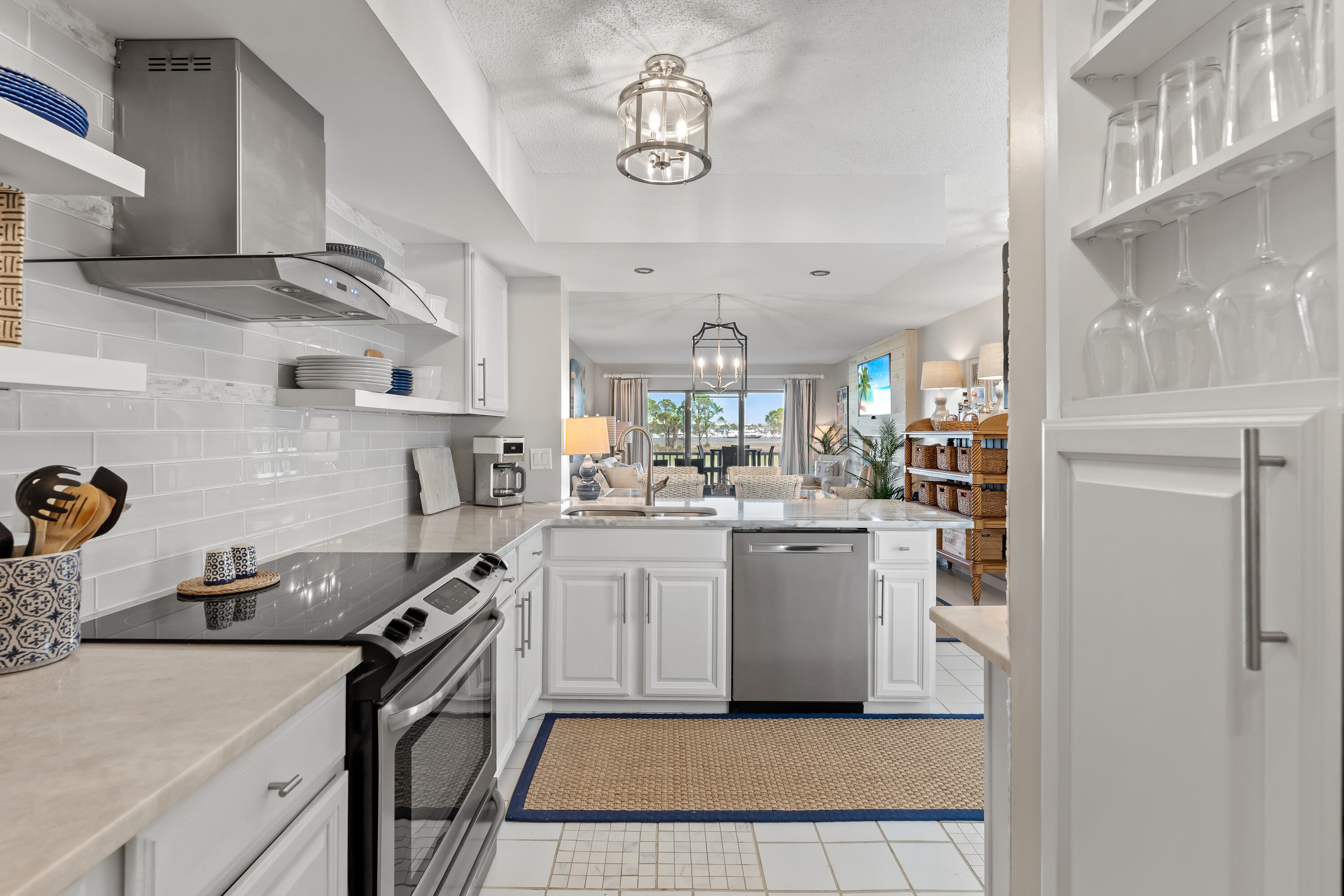 Kitchen with white cabinets and stainless appliances, opening onto a living area with a view of water.