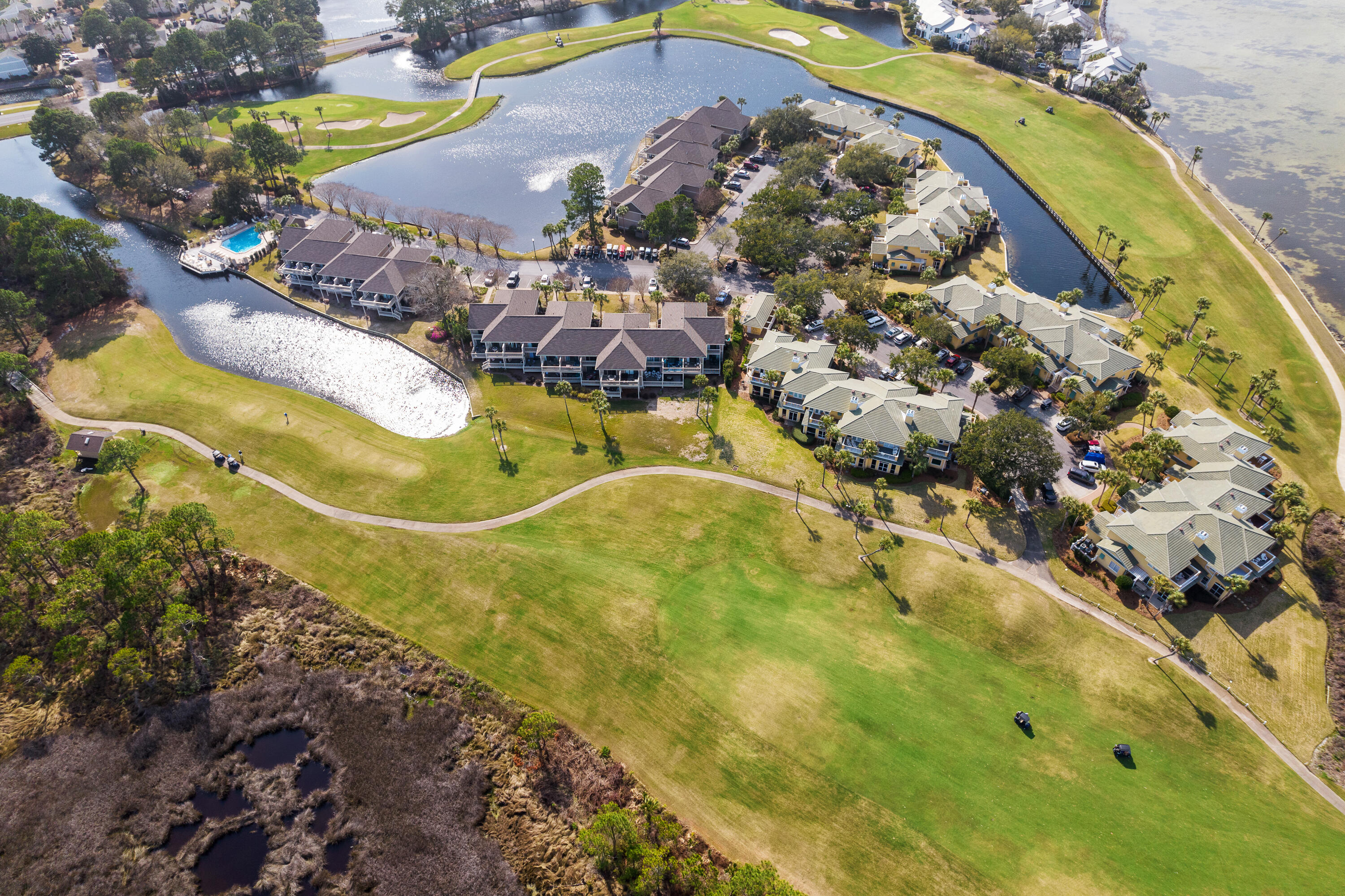 Waterfront condominiums bordered by a golf course, with a pool and waterways nearby.