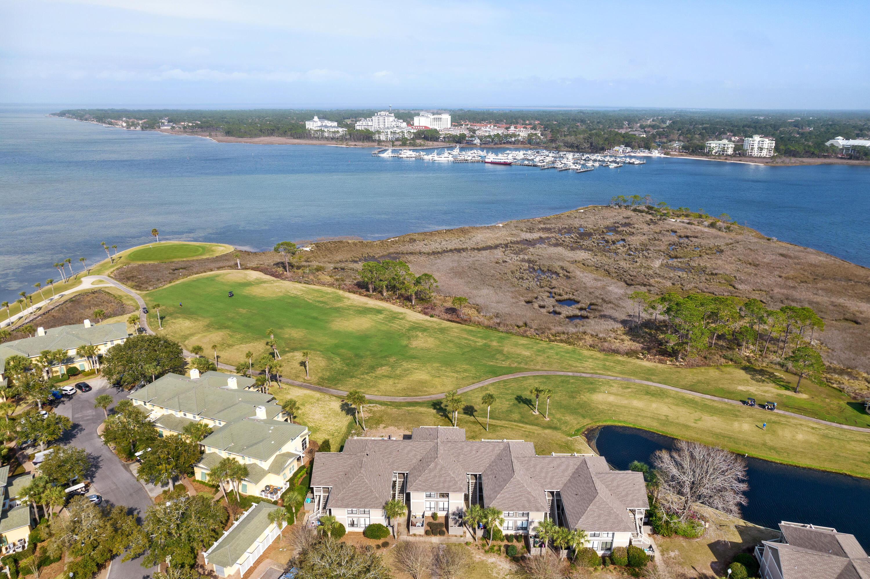 Waterfront homes beside a golf course, marshland, and bay marina.