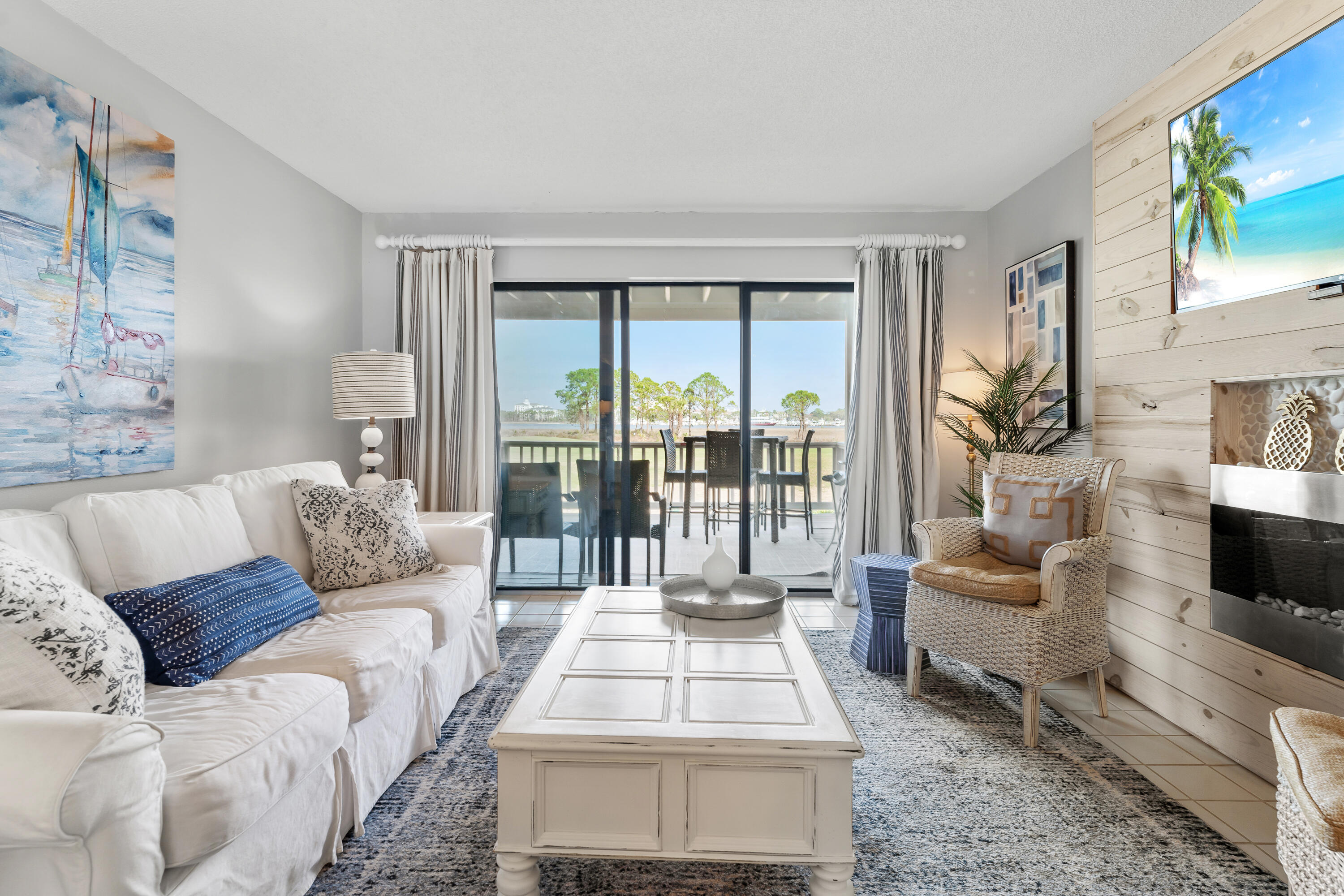 Living room with a white sofa, plank-wall fireplace, and sliding doors overlooking the water.
