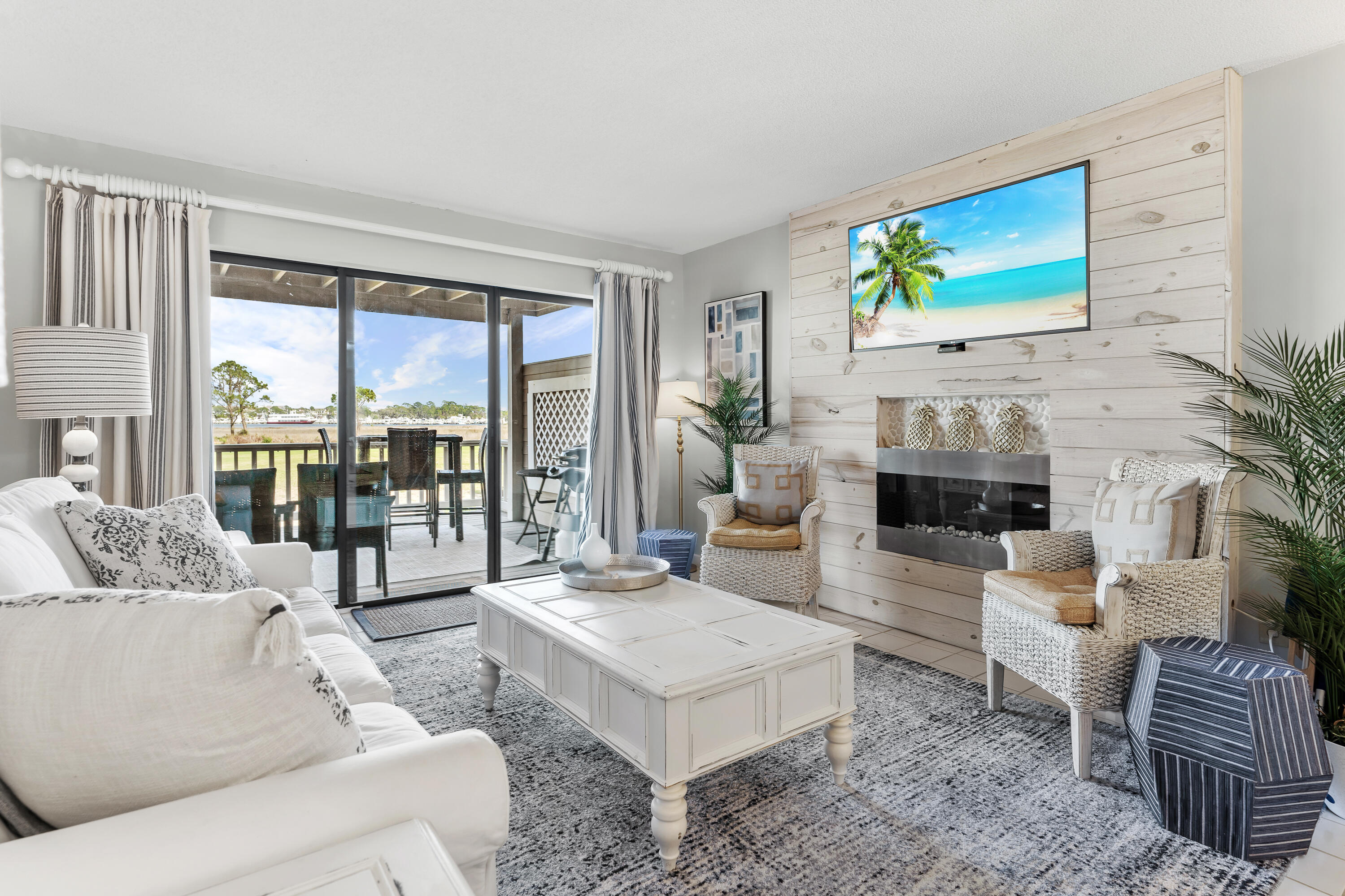 Furnished living room with a whitewashed fireplace wall and sliding doors overlooking the water.