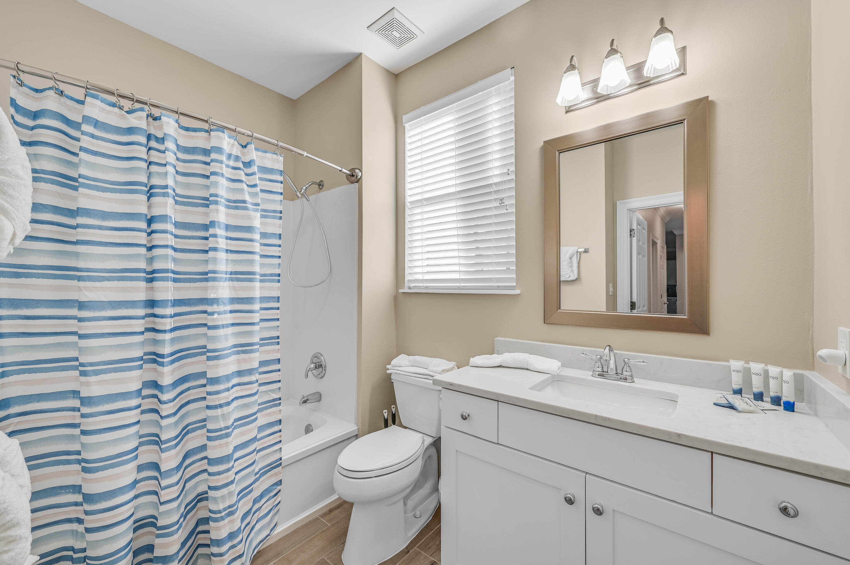 Bathroom with a blue-and-white striped shower curtain and white vanity.