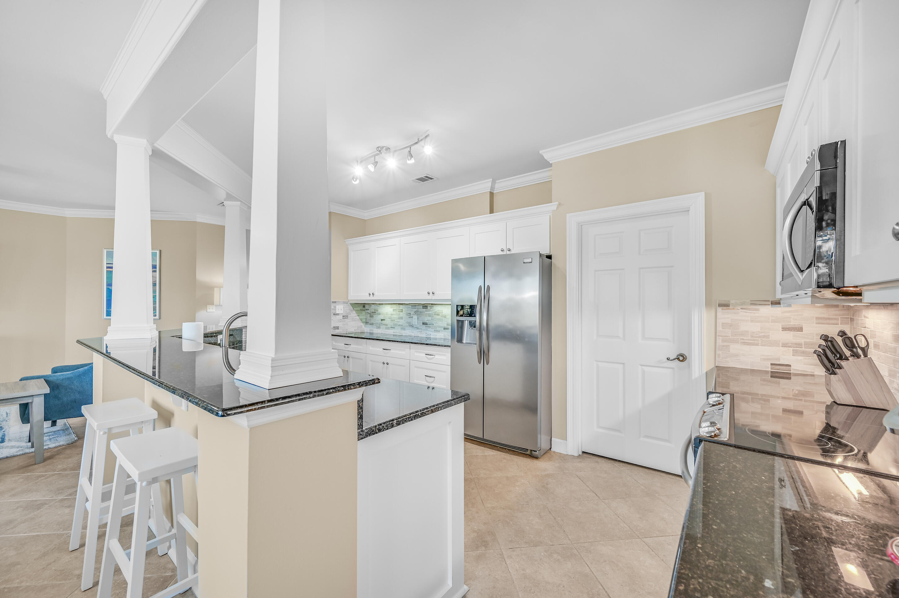 Kitchen with white cabinets, stainless appliances, dark granite counters, and a breakfast bar with stools.