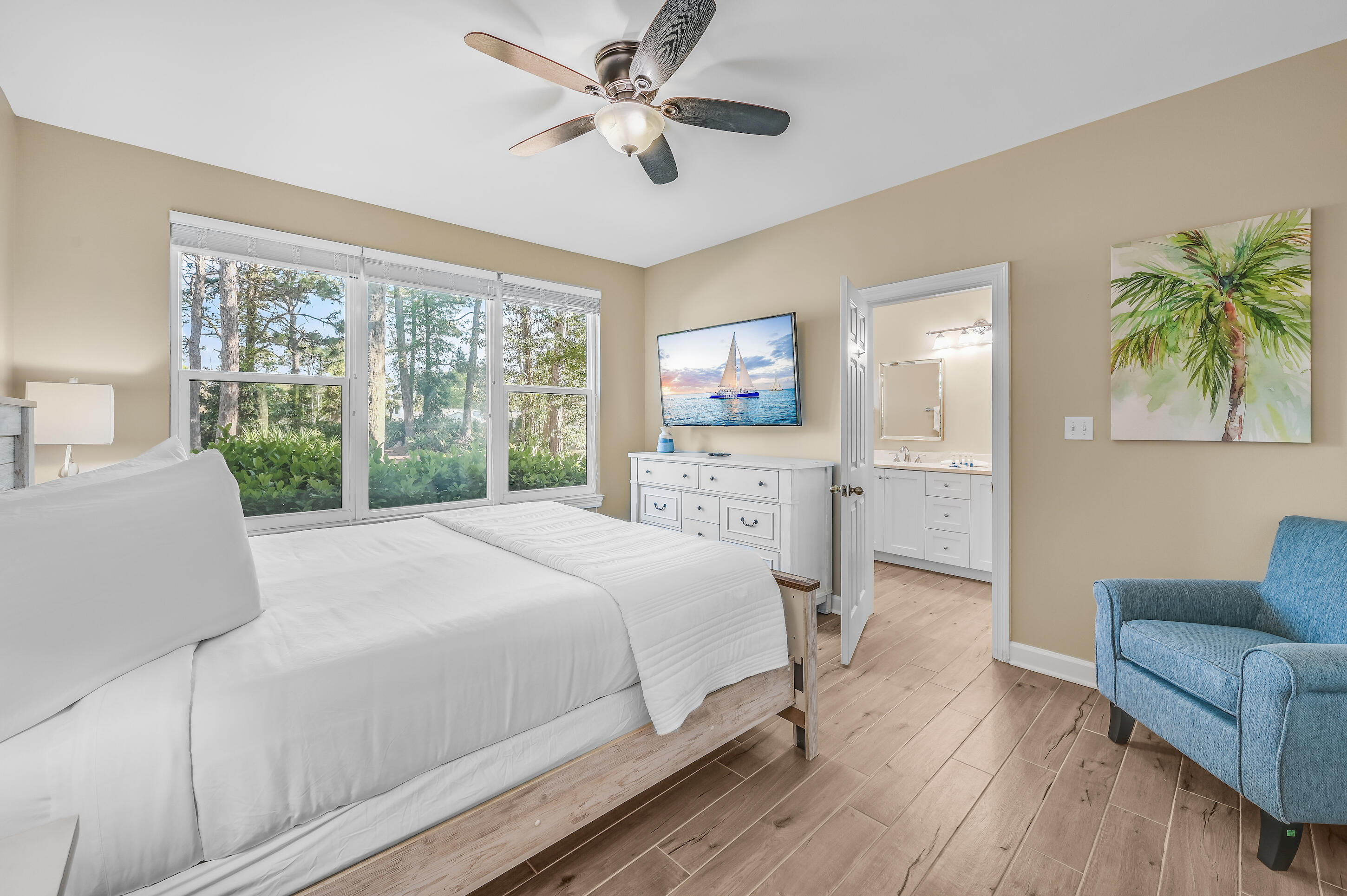 Bedroom with a white bed, large garden-facing windows, and an open doorway to the en-suite bathroom.