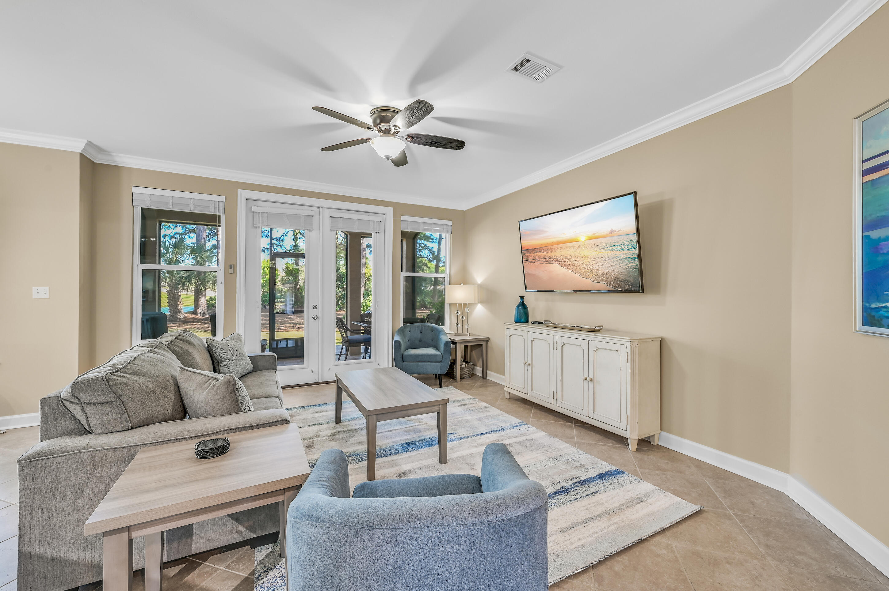 Living room with gray and blue seating and glass doors opening to a patio.