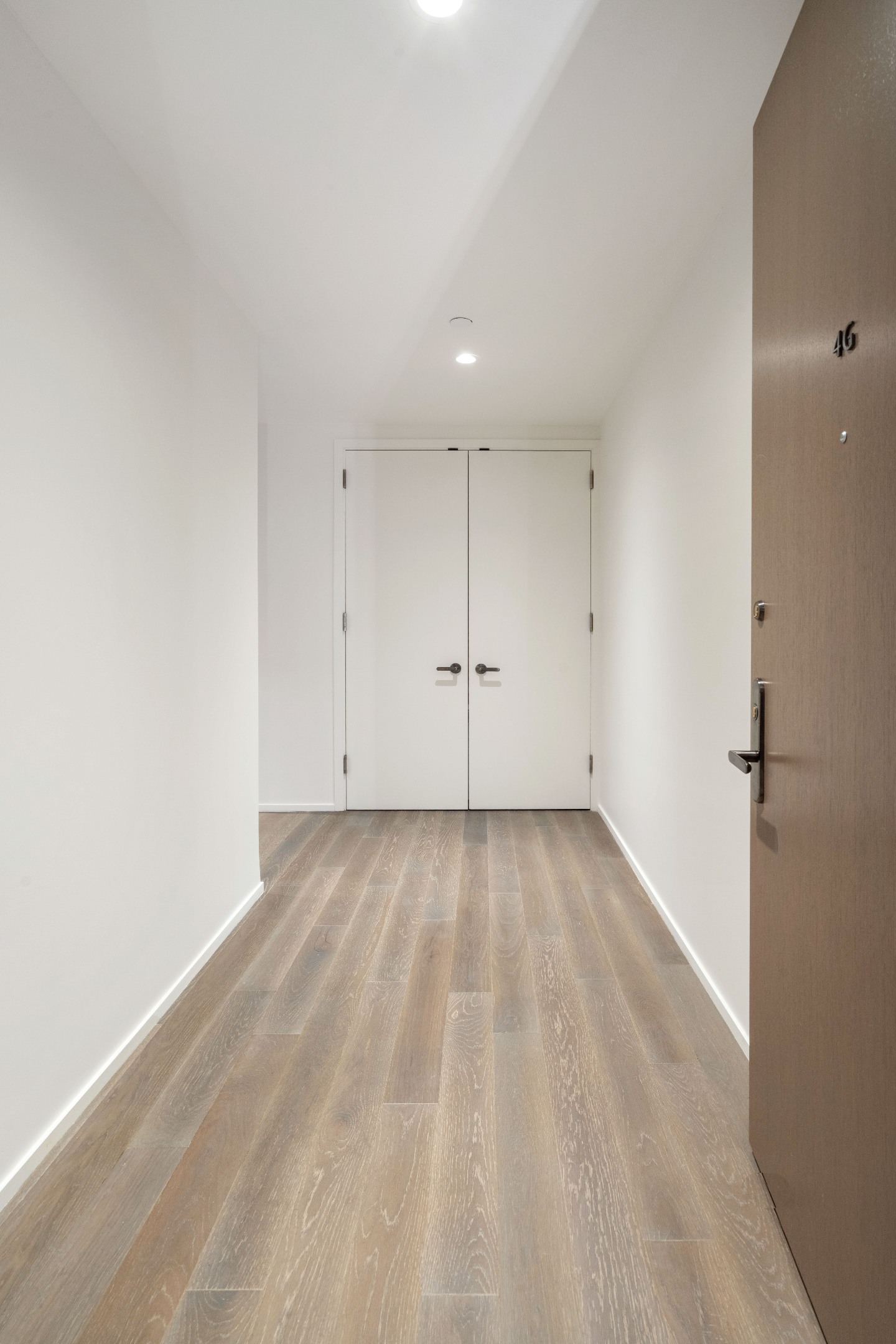 Apartment entry hall with light wood flooring, white double doors, and open unit door marked 4G.