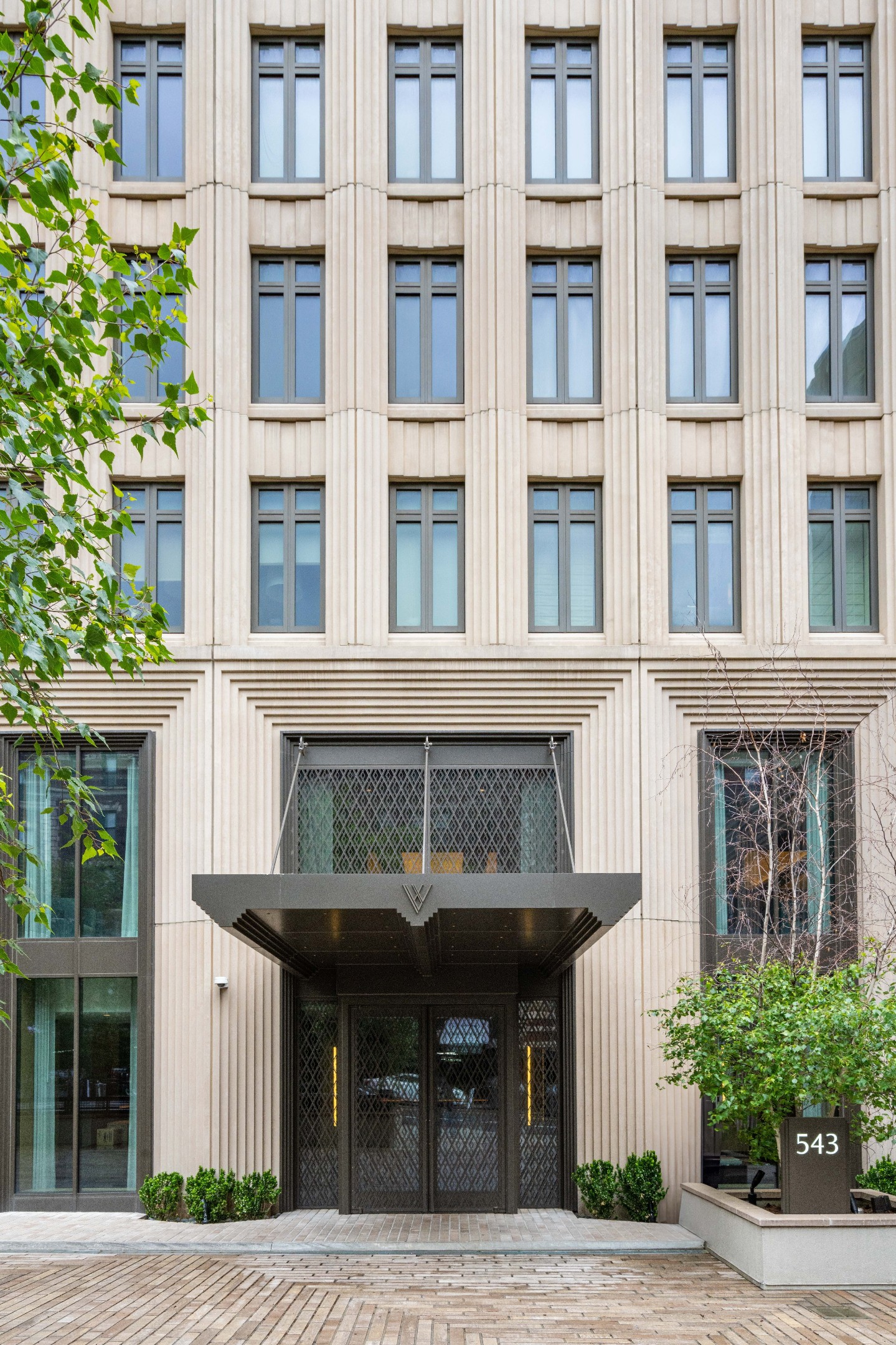 Apartment building entrance at 543 W 122nd Street, with a projecting dark canopy and tall stone facade.