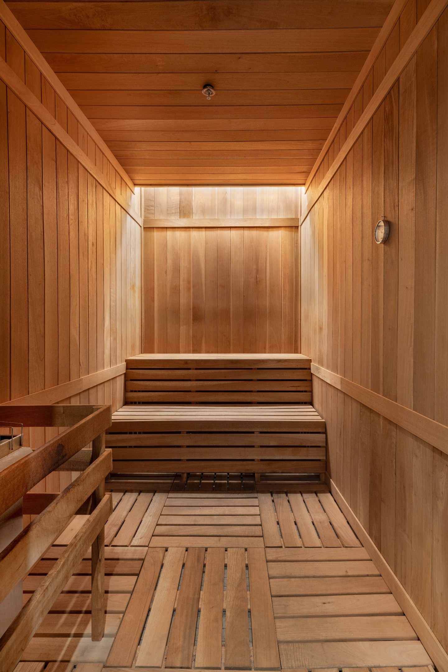 Wood-paneled sauna with tiered benches and a wall thermometer.