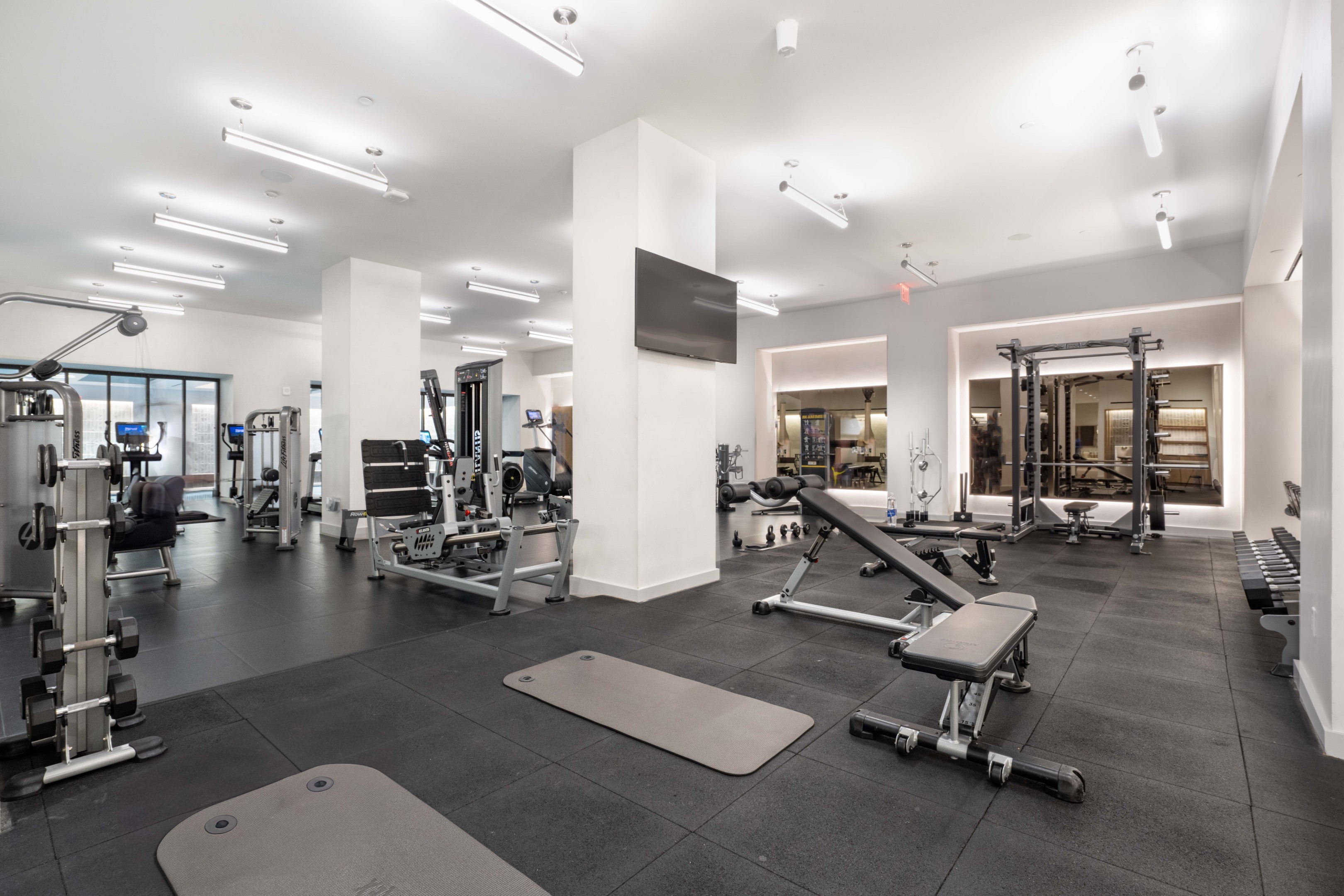 Fitness center with weight machines, dumbbells, benches, and exercise mats.