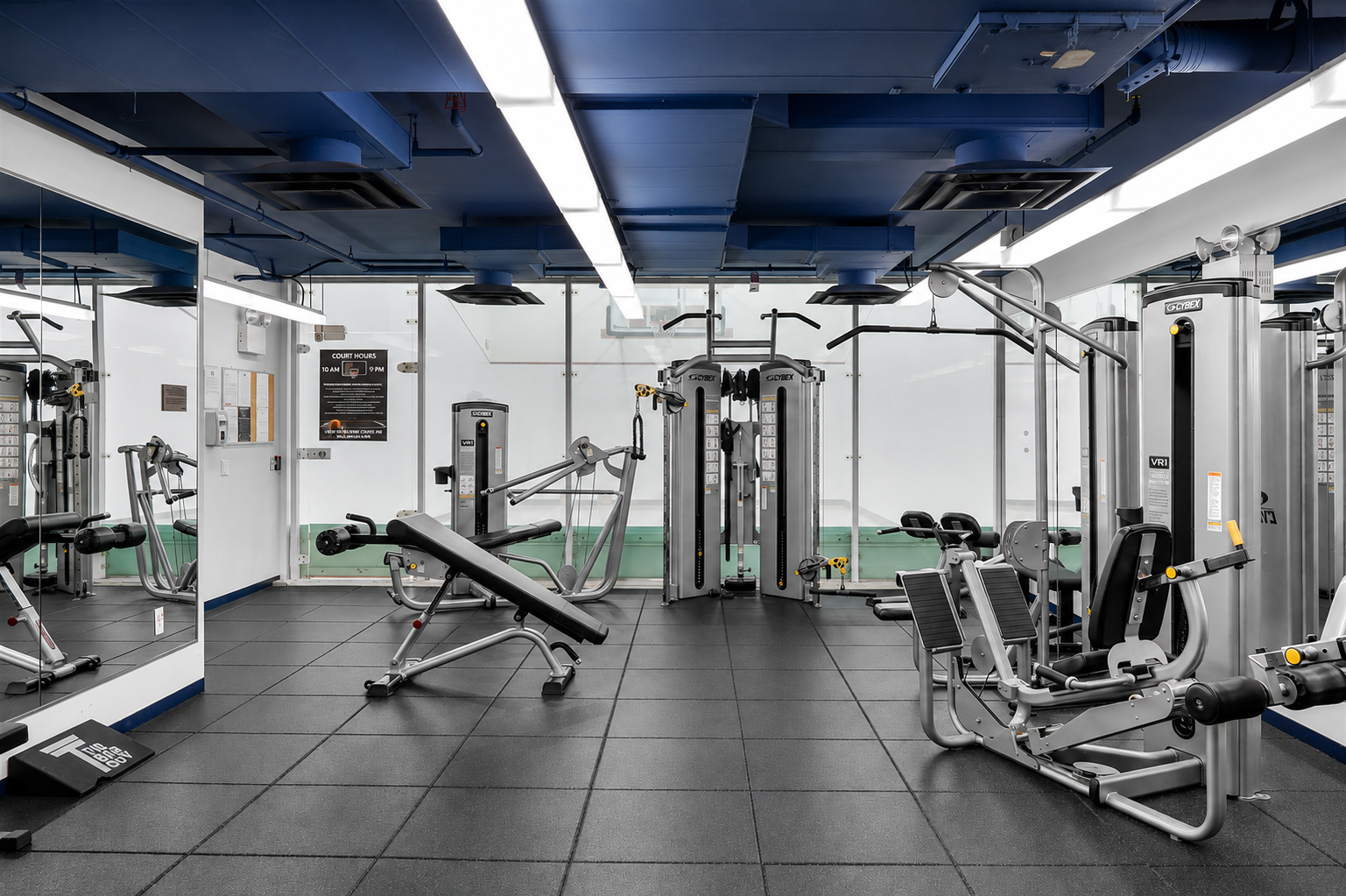 Fitness room with strength-training machines, weight benches, and a mirrored wall.