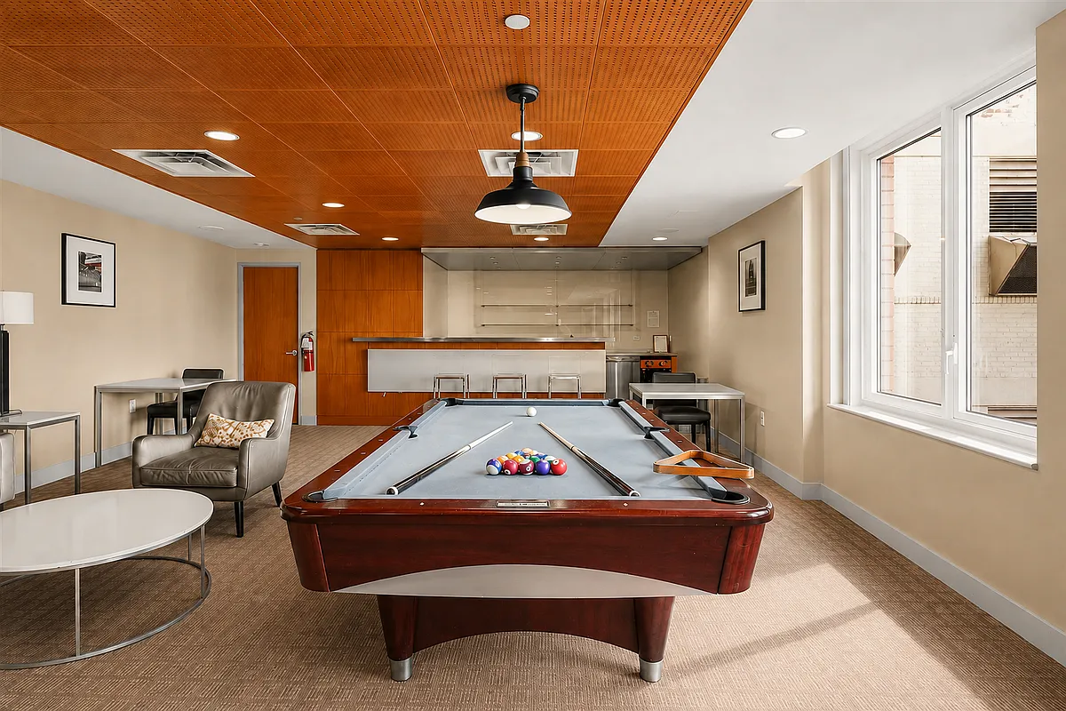 Building game room with a pool table, lounge seating, and a wood-paneled ceiling.