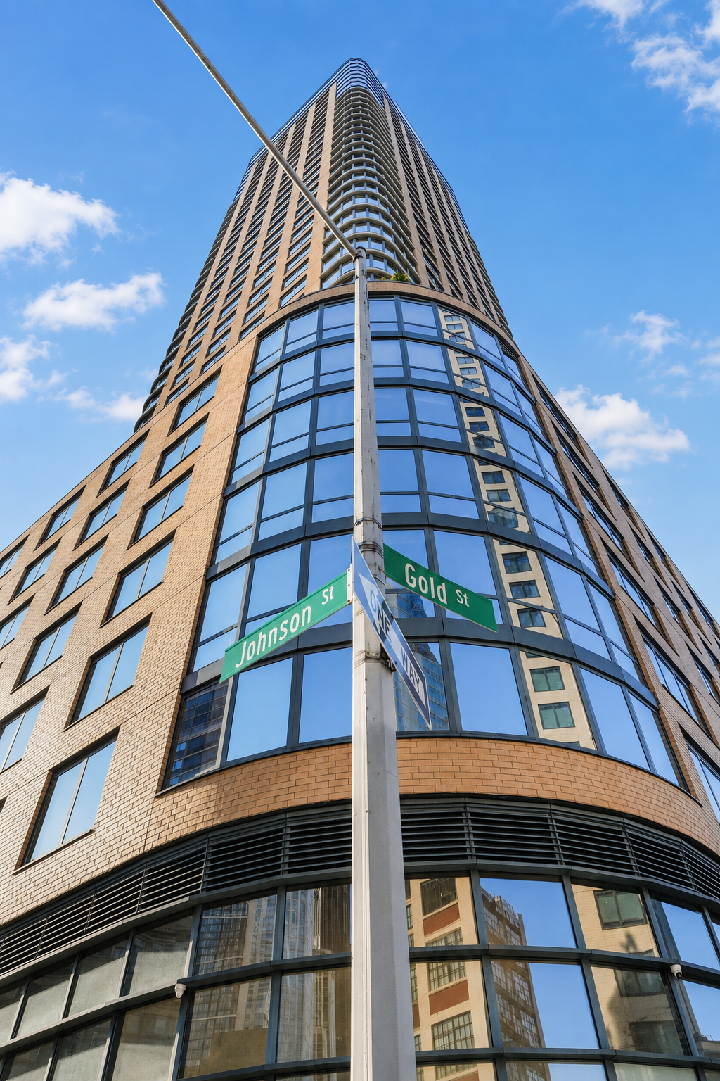 Brick-and-glass residential tower with a rounded corner at Johnson Street and Gold Street.