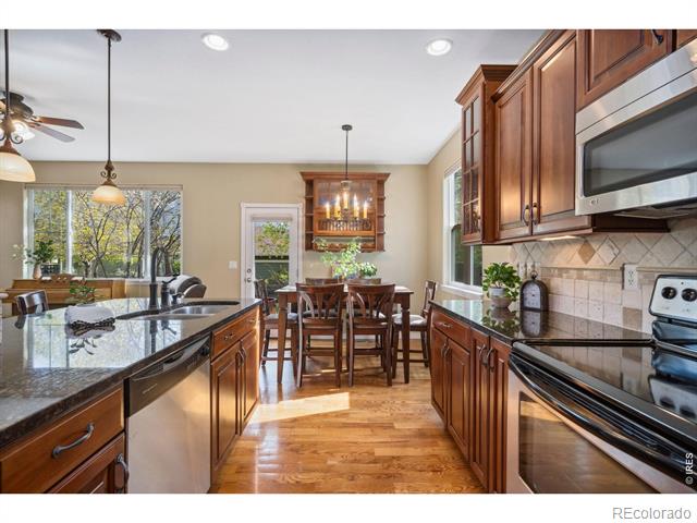 Kitchen with wood cabinetry, granite island, stainless appliances, and a dining area by the windows.