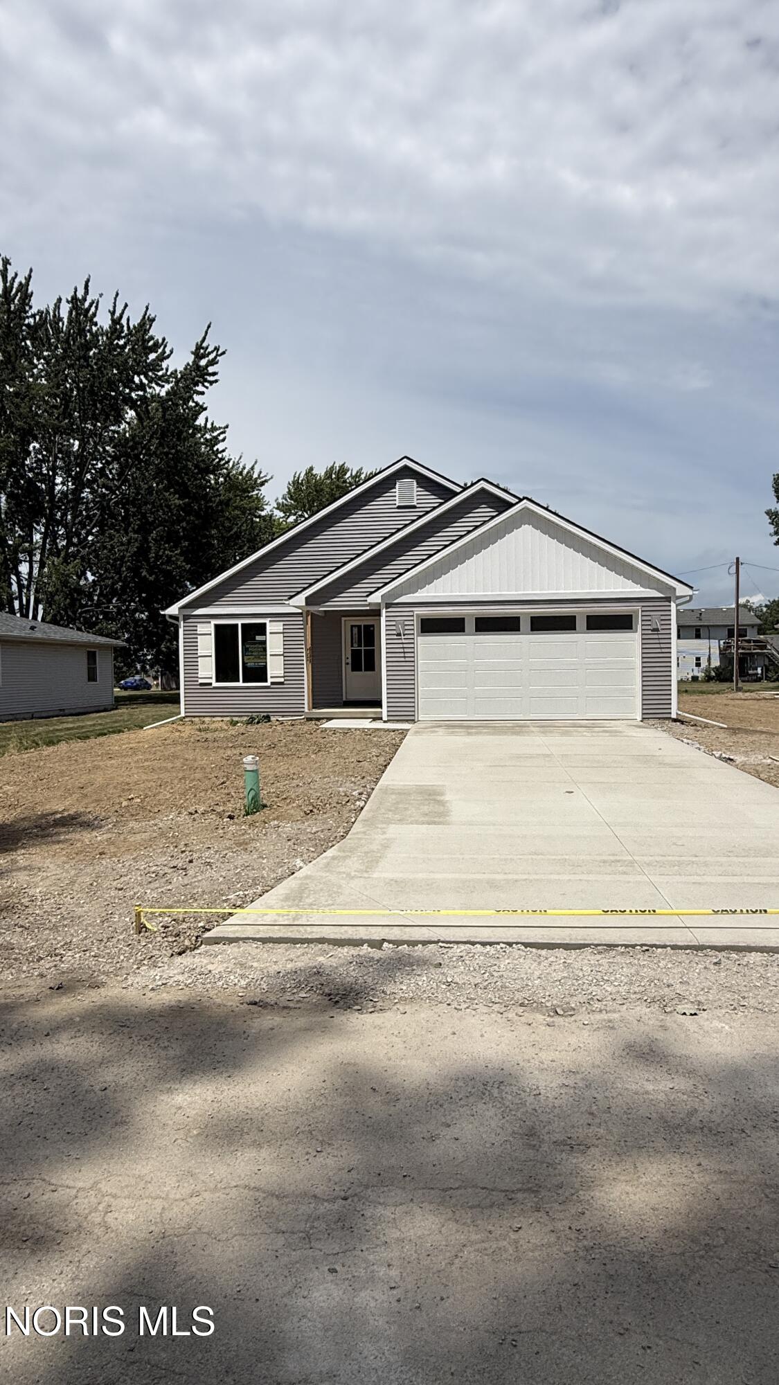 New single-story gray house with a white double garage door and unfinished front yard.