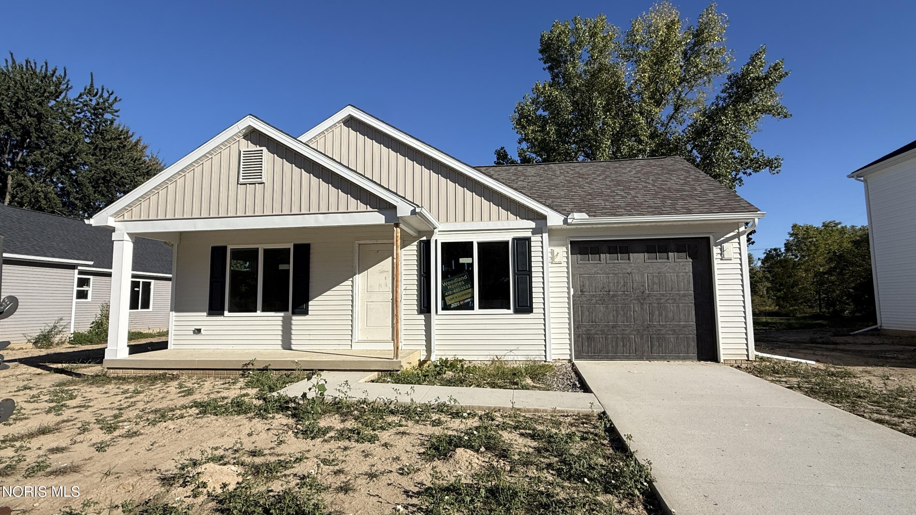 New single-story home with a covered porch, multiple gables, and a dark garage door.