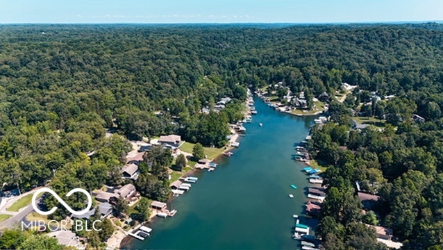 Aerial view of a wooded lake lined with homes, docks, and boats.