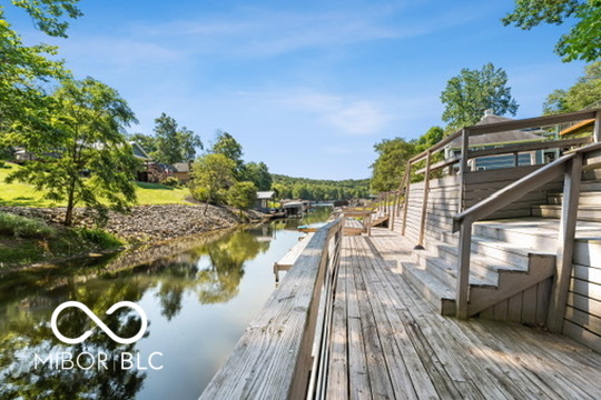 Wooden waterfront deck beside a calm, tree-lined channel.