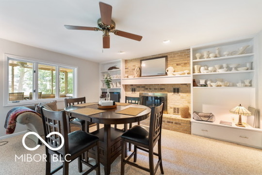 Dining room with a round table, large windows, and a brick fireplace with built-in shelves.