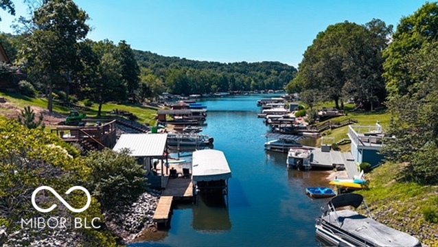 A tree-lined lake cove with boat docks and boats along both shores.