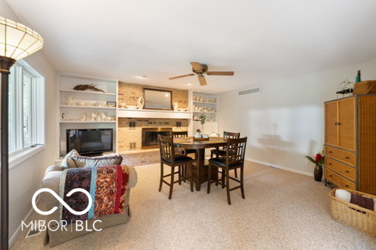 Living and dining area with built-in shelves, a fireplace, and a wooden dining table.