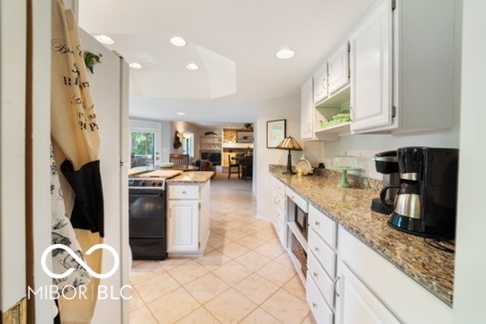 Kitchen with white cabinets, granite countertops, tiled floor, and stainless-steel appliances.