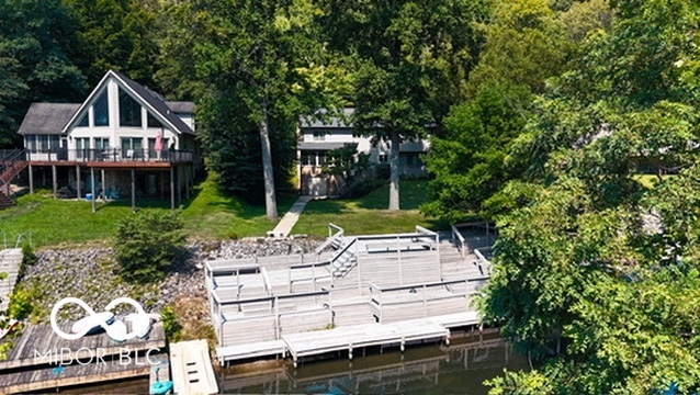 Waterfront property with wooded shoreline, two homes, and a large tiered dock.