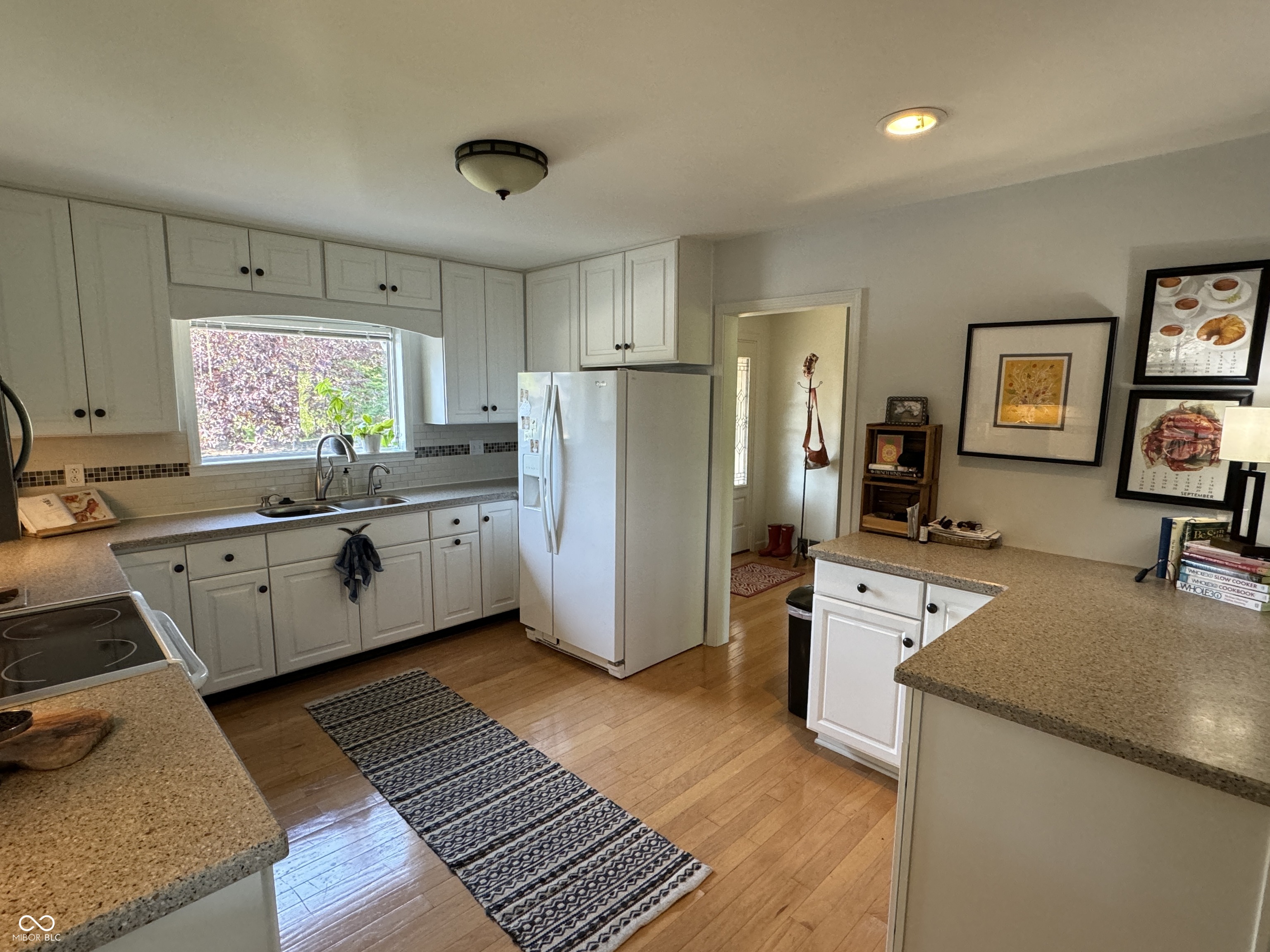 Kitchen with white cabinetry, a broad peninsula, and hardwood floors.