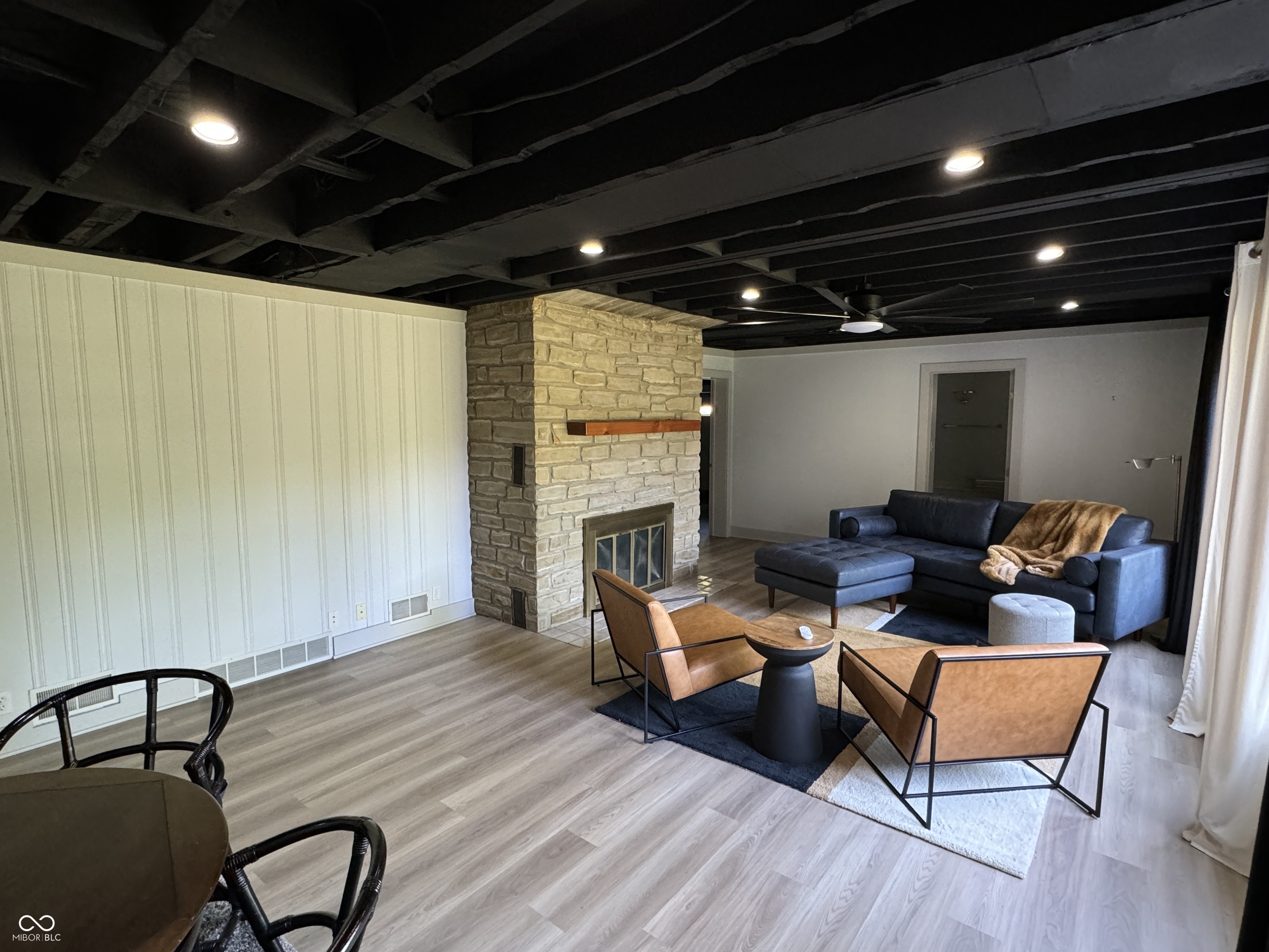 Living room with a stone fireplace, exposed ceiling beams, and a blue sectional sofa.
