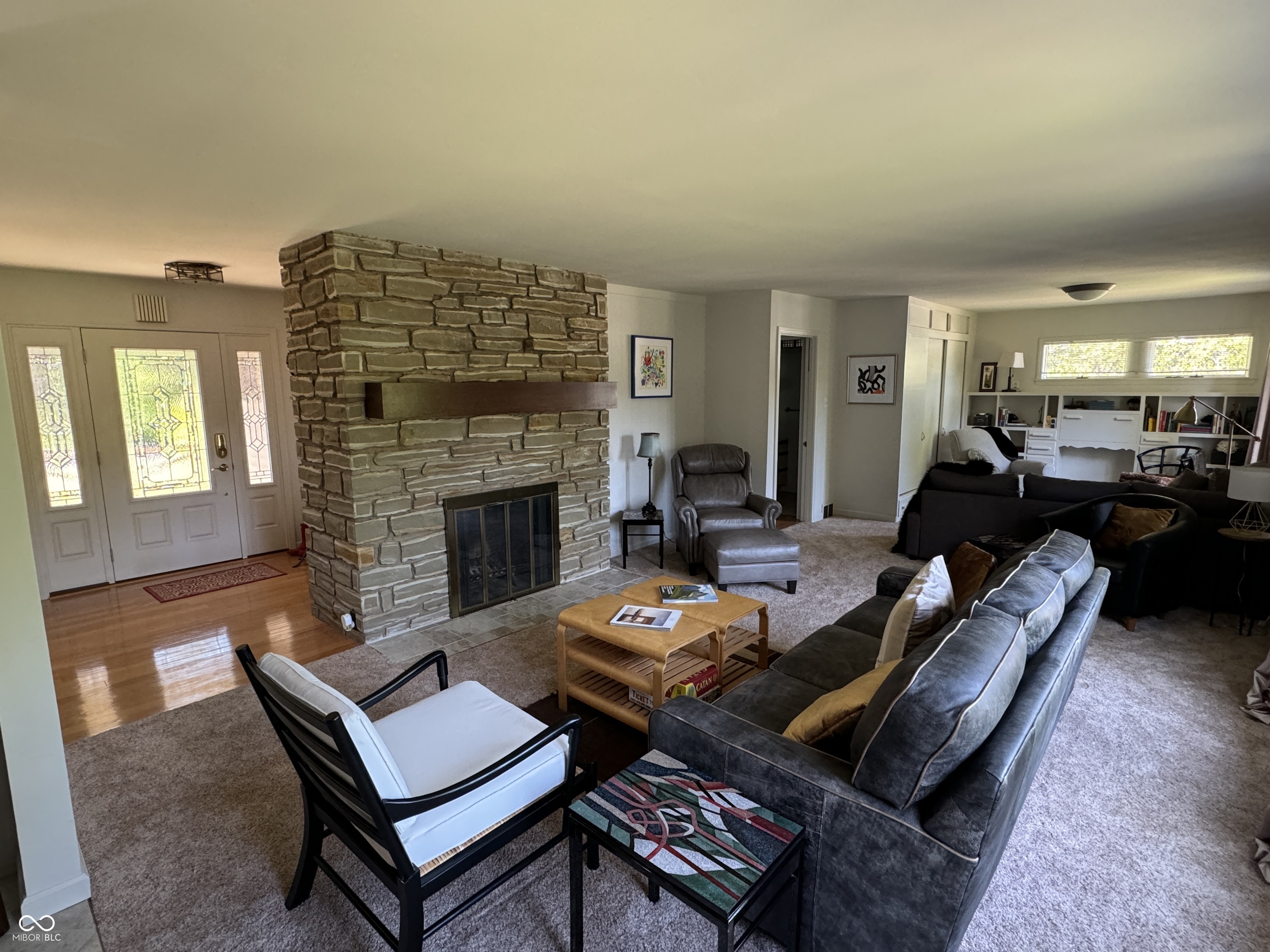 Living room with a large stone fireplace, gray sofas, and built-in shelving.