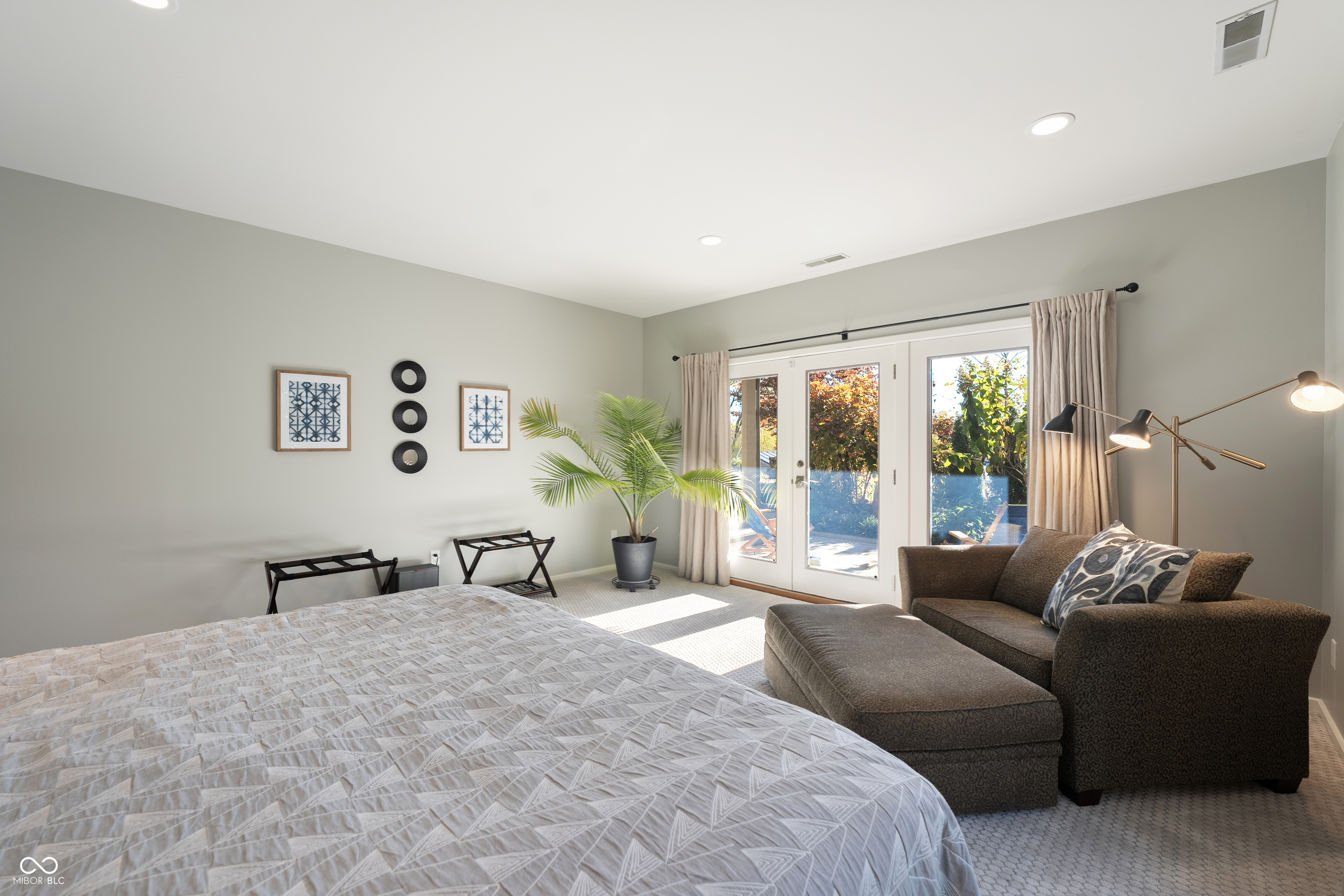 Furnished bedroom with a large bed, brown chaise lounge, and glass doors to the patio.