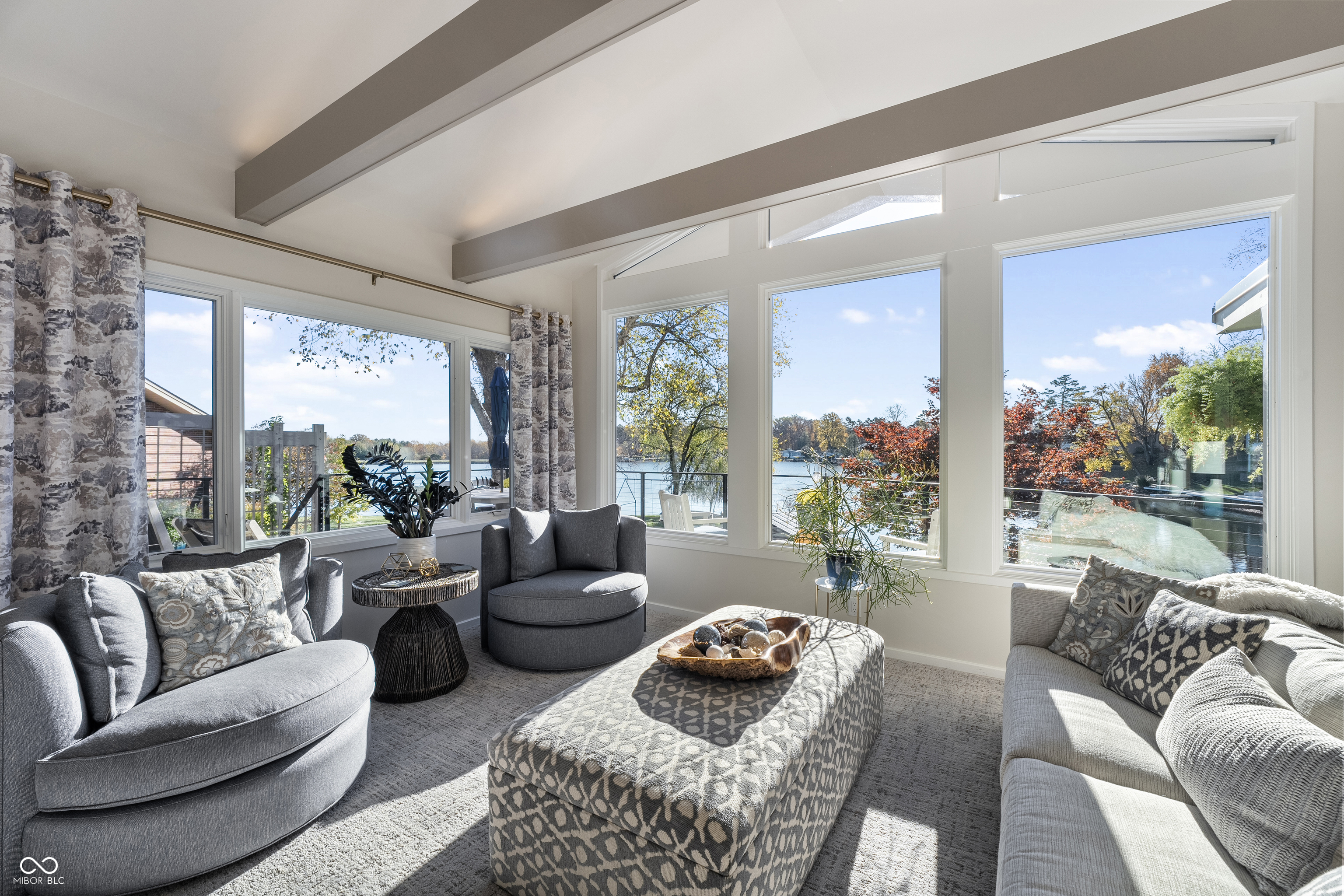 Living room with gray seating and large windows overlooking a lake.