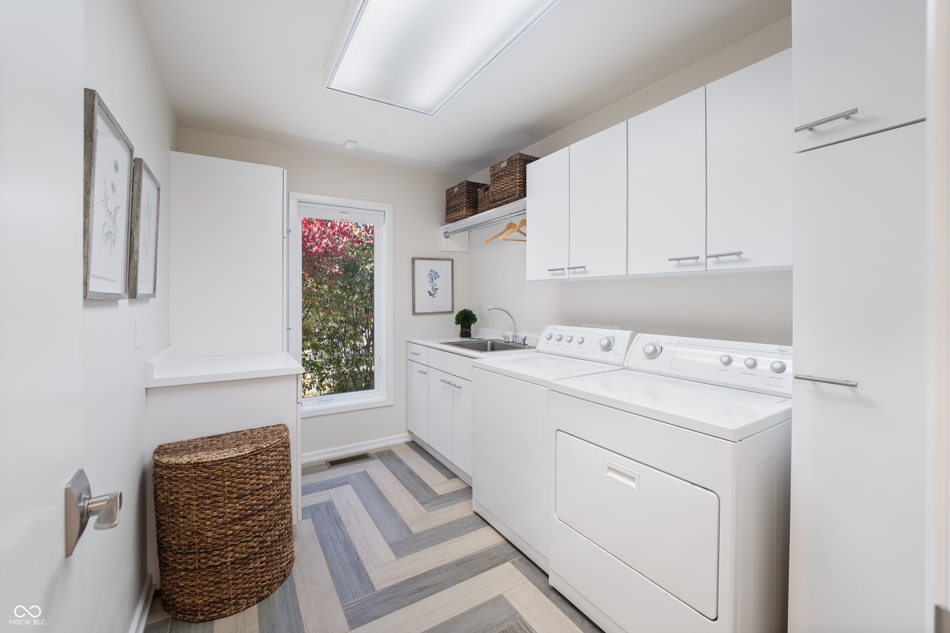 Laundry room with white washer and dryer, utility sink, and gray-and-beige patterned flooring.