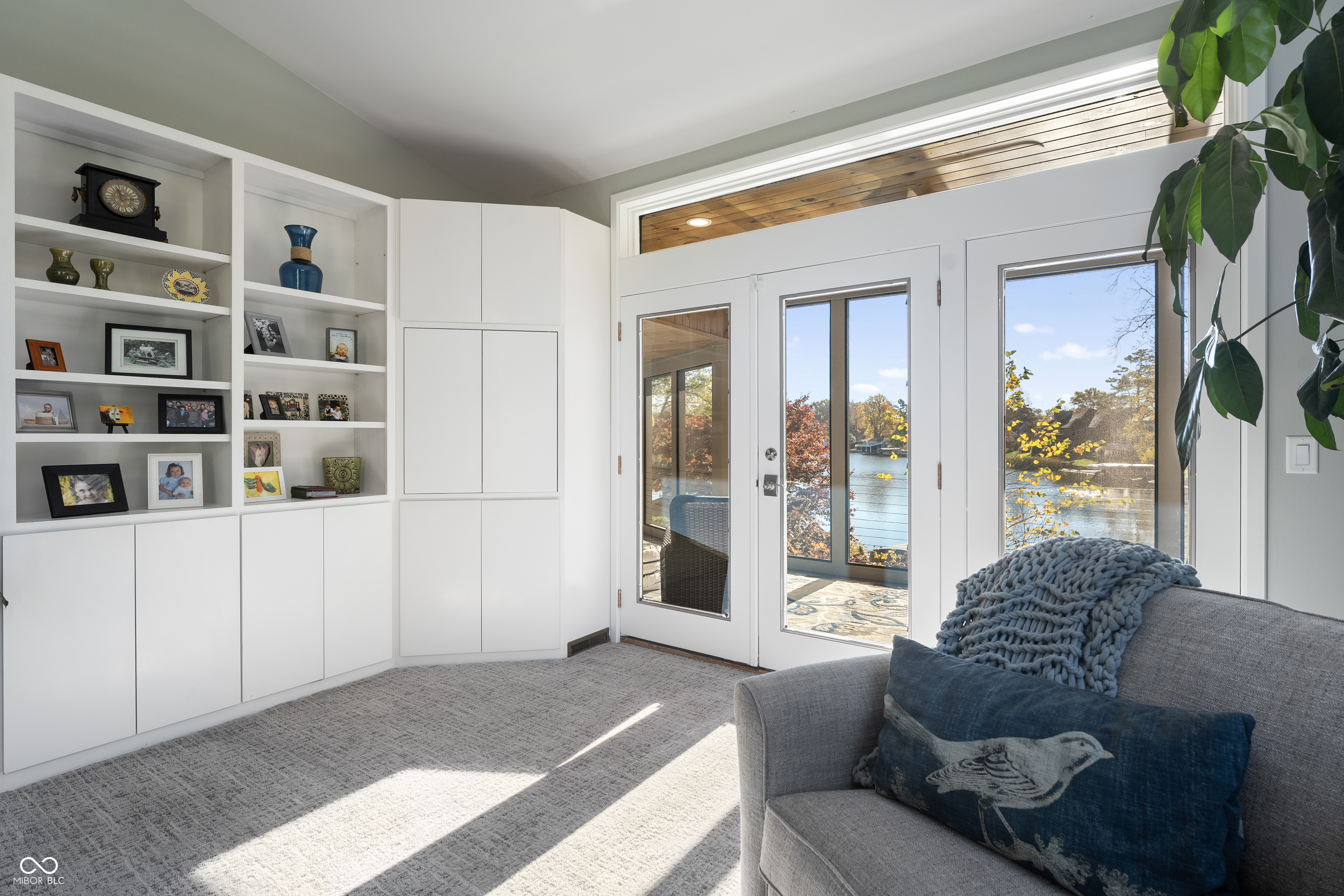 Furnished living room with built-in shelves and glass doors overlooking the water.