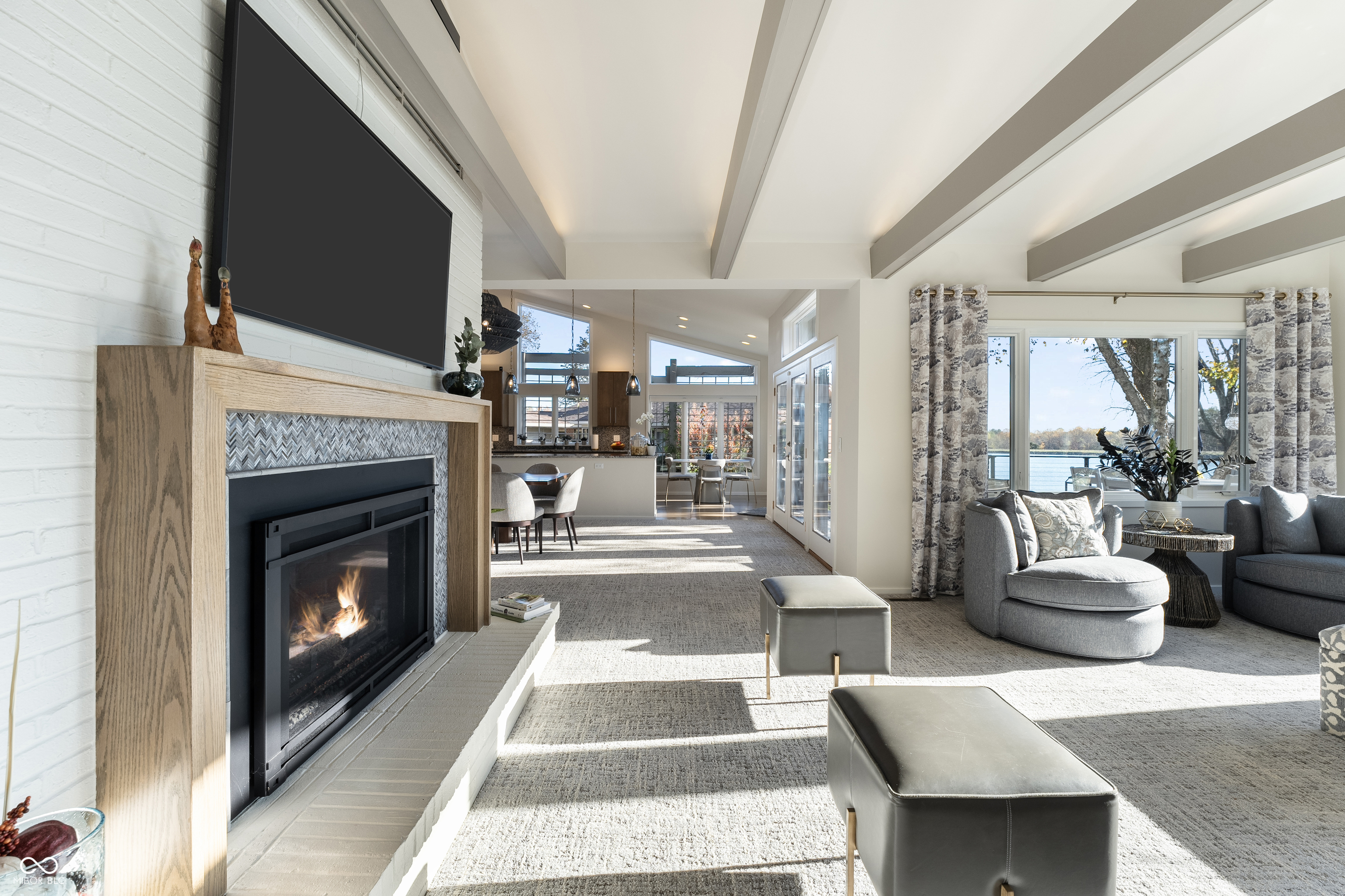 Living room with a fireplace, vaulted ceiling, and lake views through large windows.