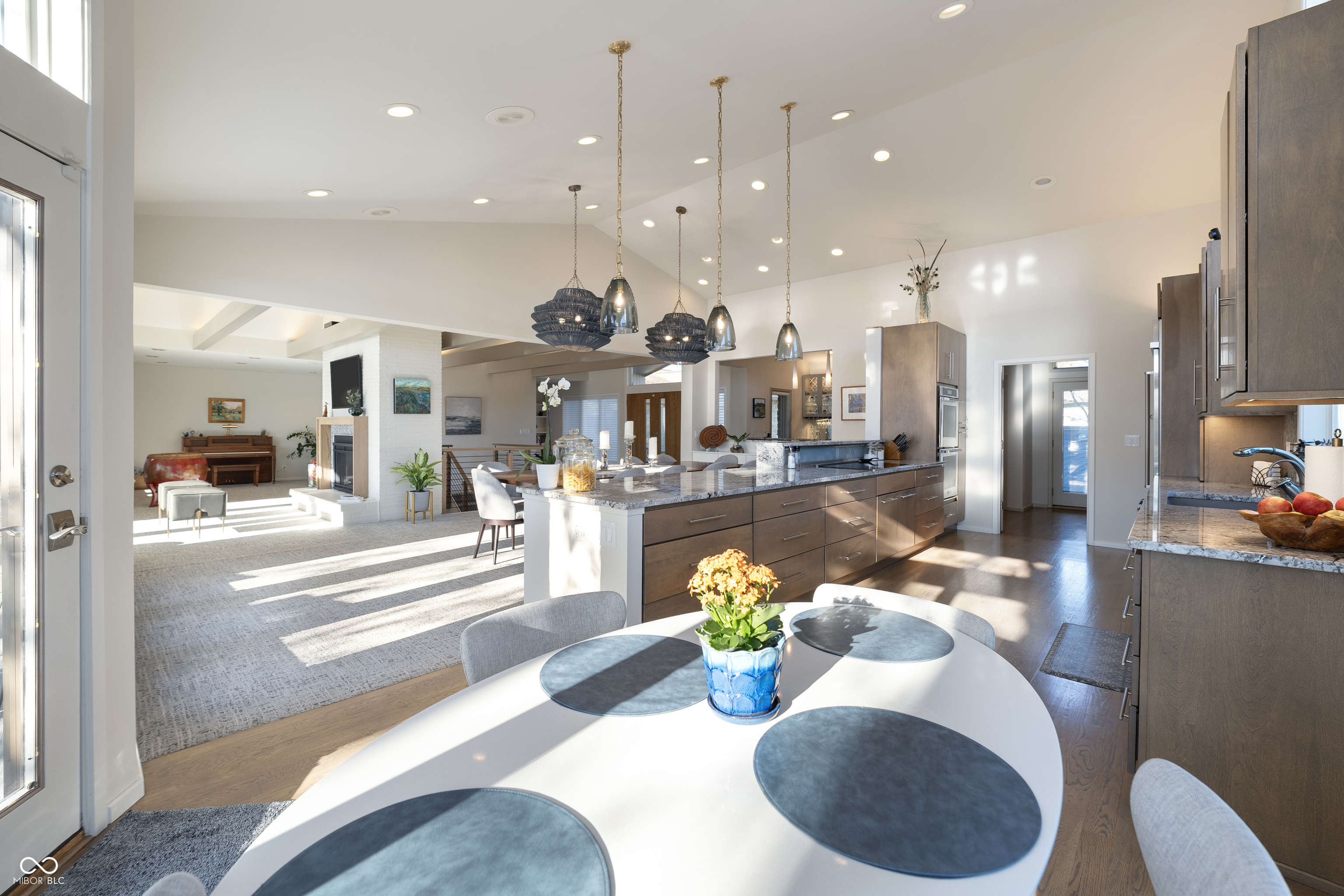 Open-plan kitchen and living room with a long island, pendant lights, and round dining table.